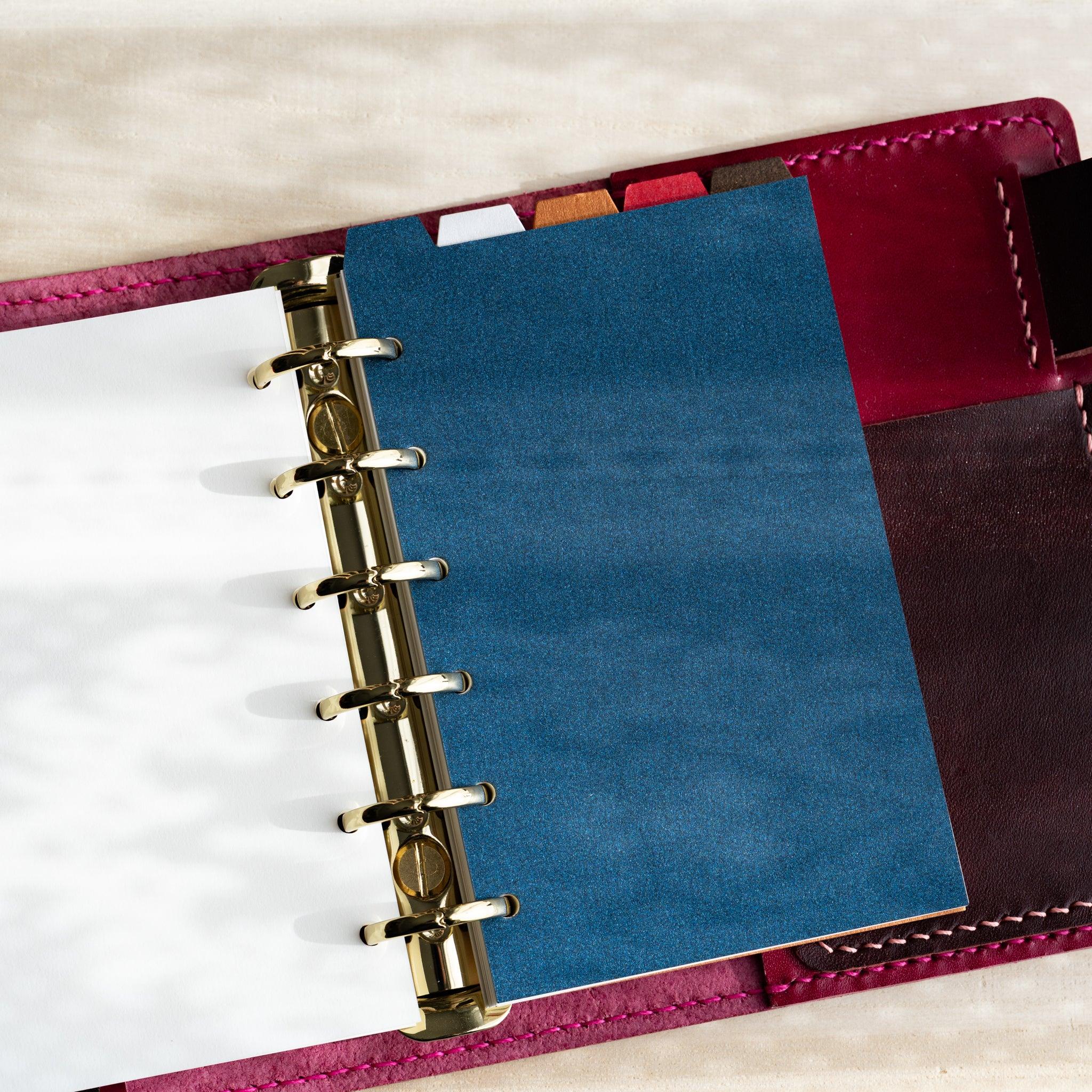 Japanese Stationery Stardream top-tab index divider for Mini 6 planners in blue inserted in an open planner with gold rings.