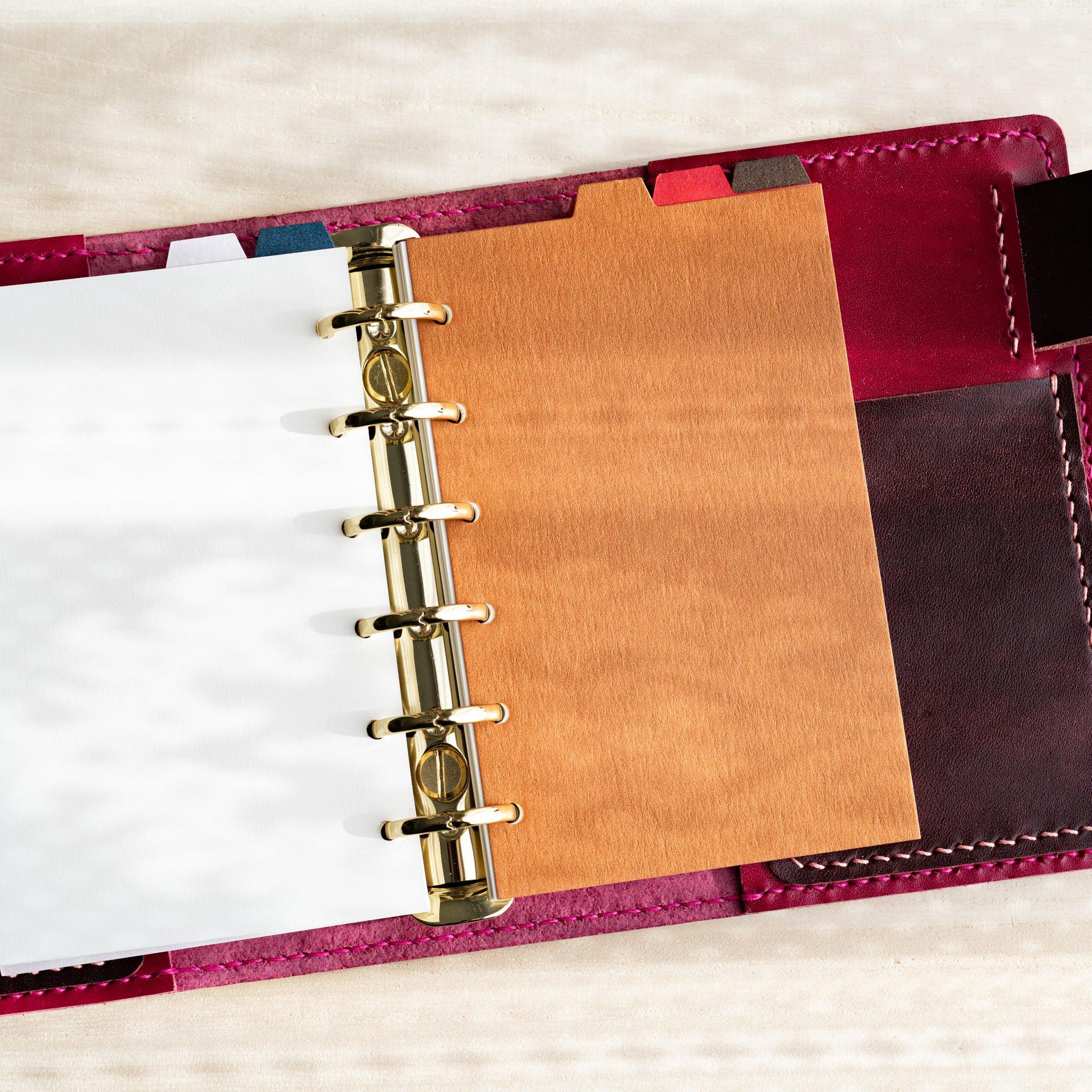 Japanese Stationery Stardream top-tab index divider inserted in a Mini 6 planner with gold rings and a brown sheet.