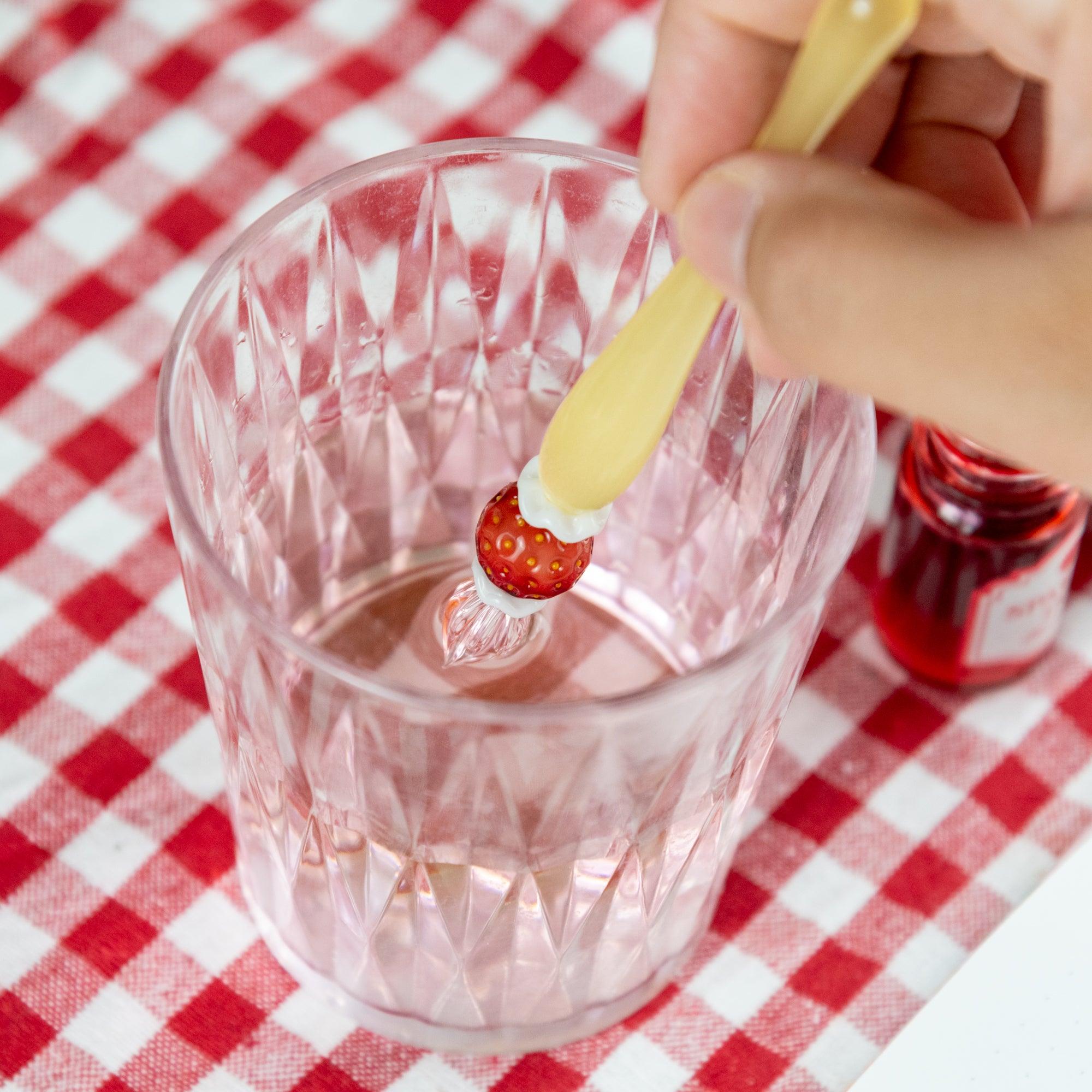 Hand rinsing a strawberry-themed glass pen in water. Perfect for Japanese stationery fans.