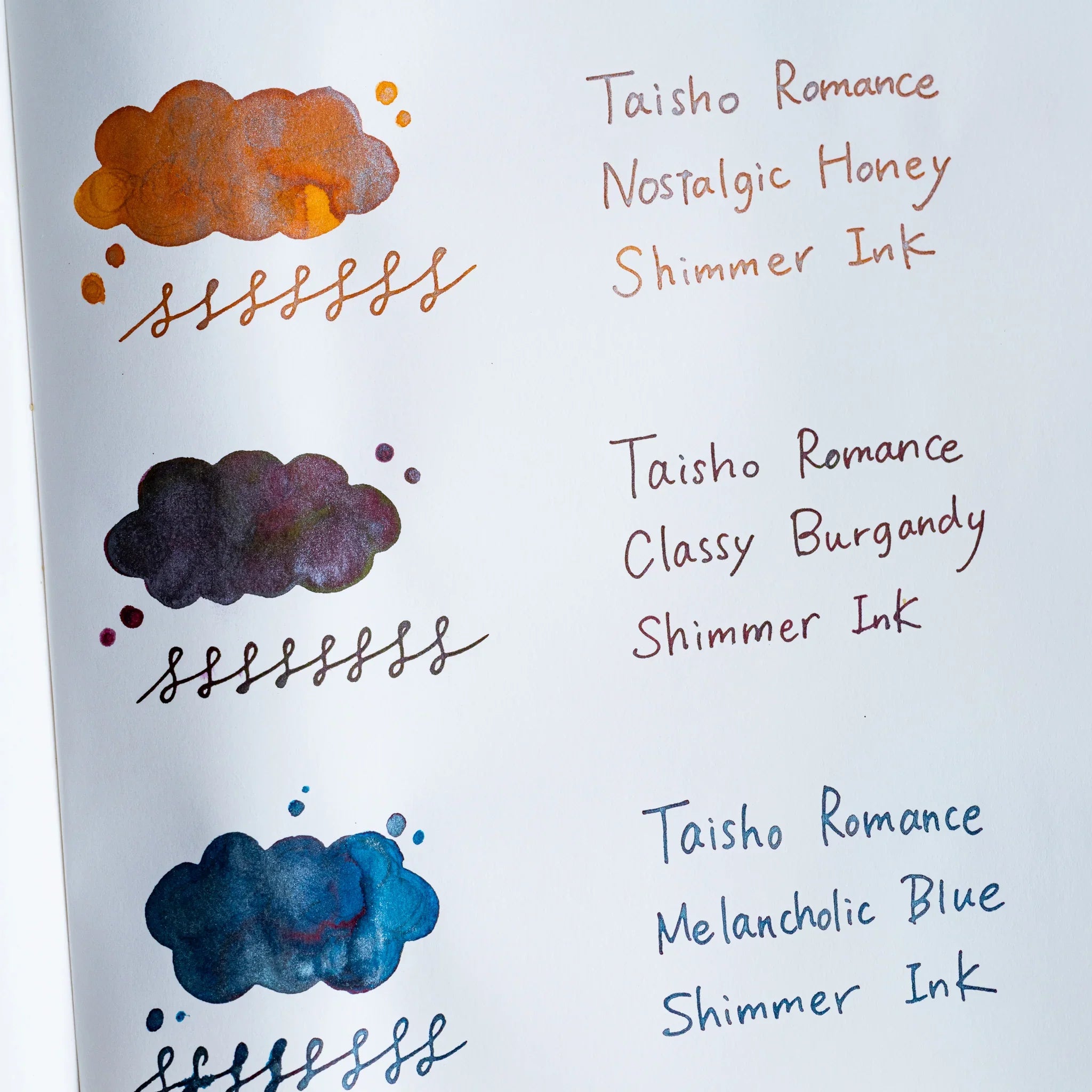 Handwritten swatch of Taisho Romance Classy Burgundy Shimmer Ink, a cloud-shaped wash and looped line with silver flecks
