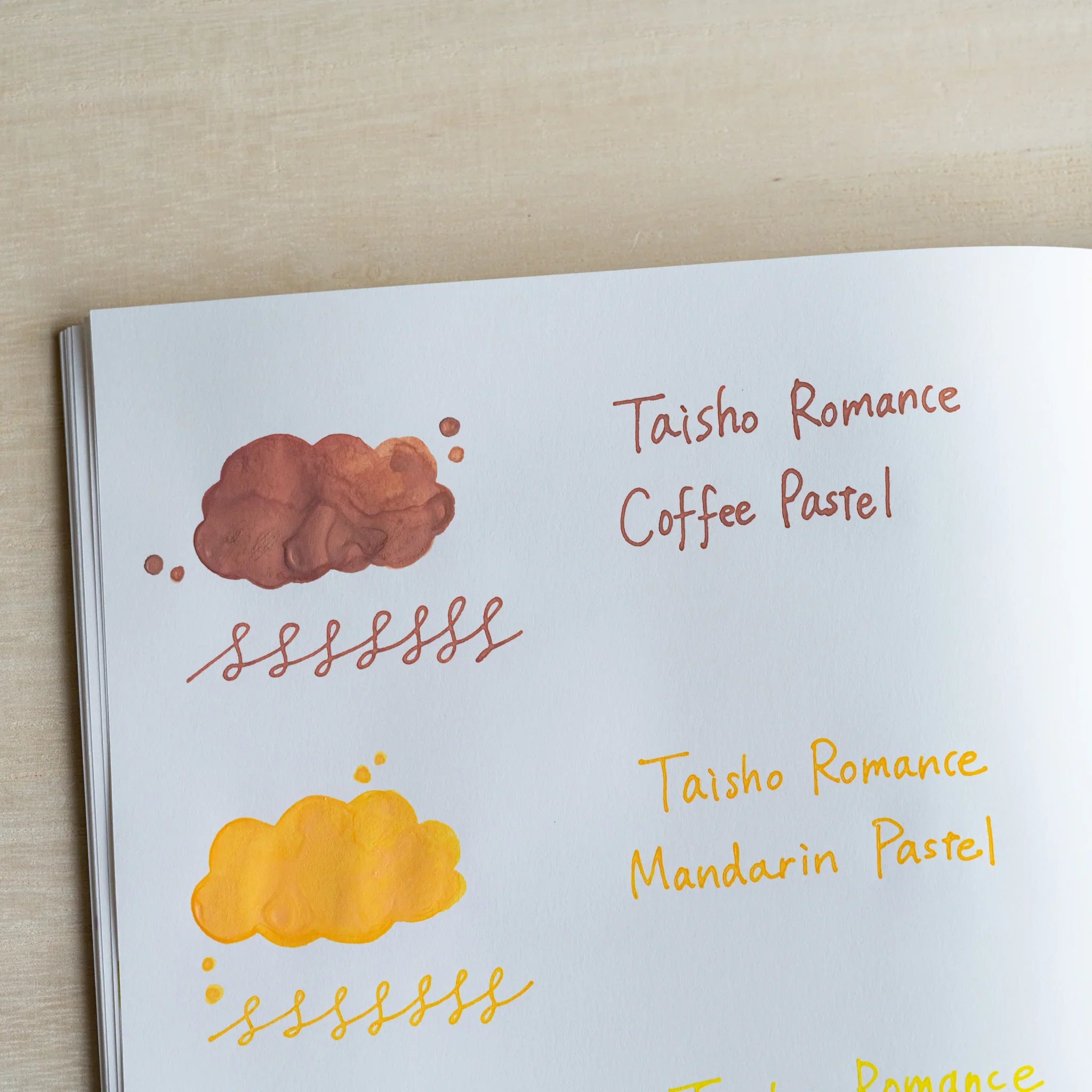 Handwritten swatch of Taisho Romance Coffee Pastel ink, a cloud-shaped wash and a looped line in reddish brown