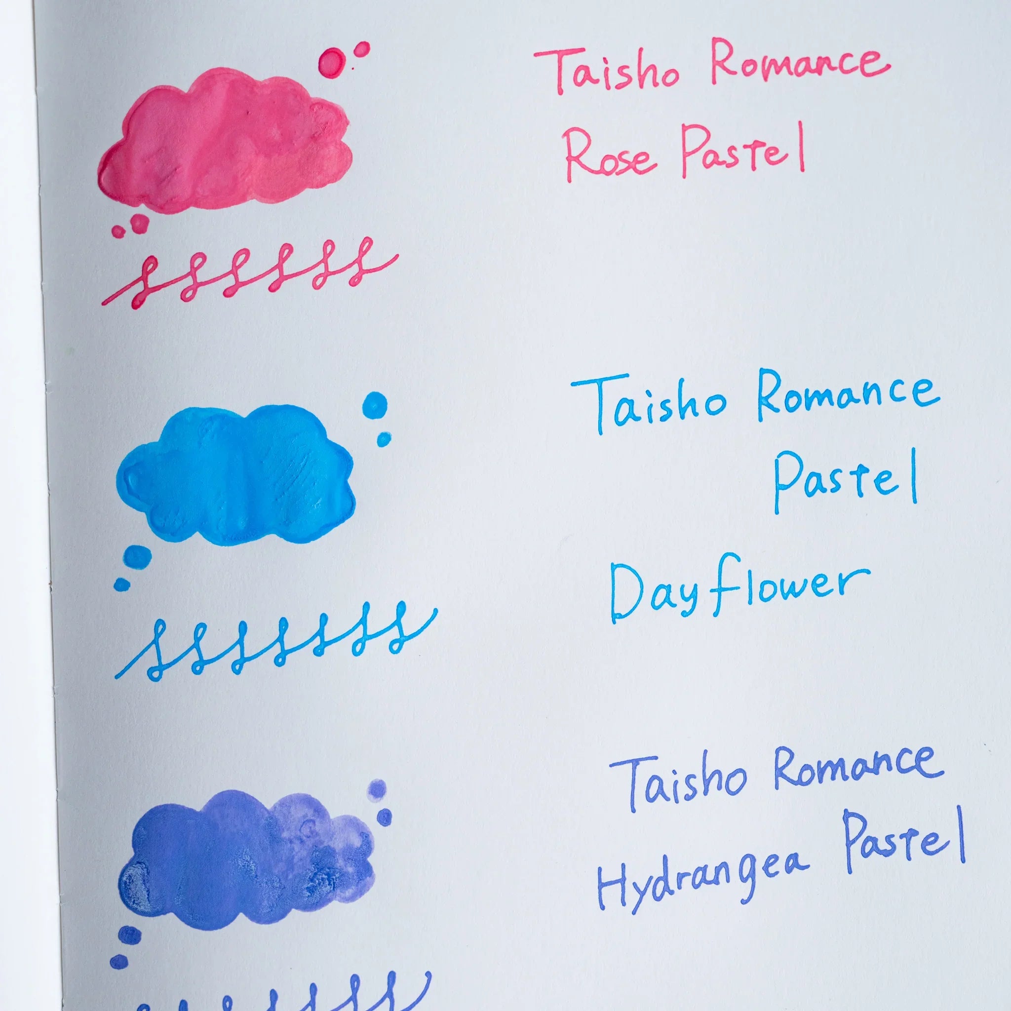 Handwritten swatch of Taisho Romance Dayflower Pastel ink, a cloud-shaped wash and a looped line in cyan blue