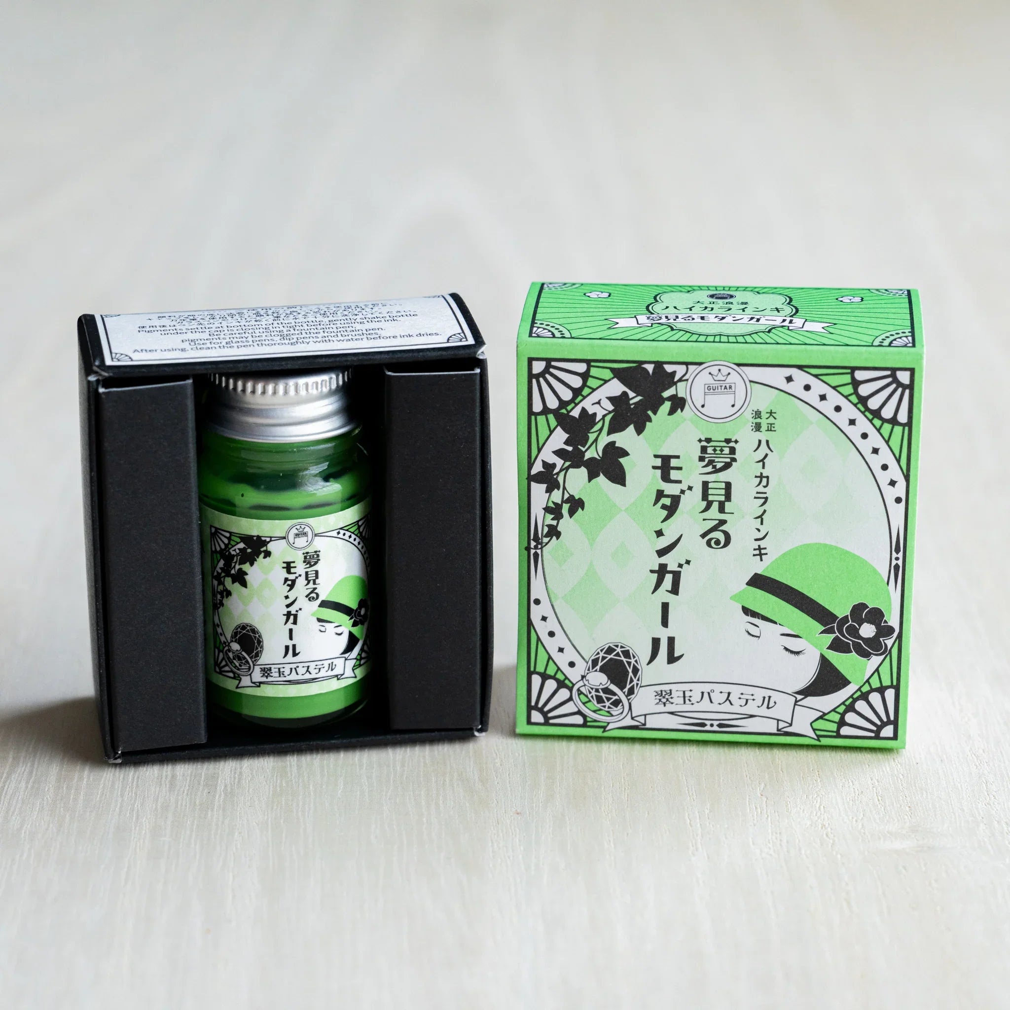 Taisho Romance Jade Pastel ink bottle in its open black inner box, next to the closed green outer box