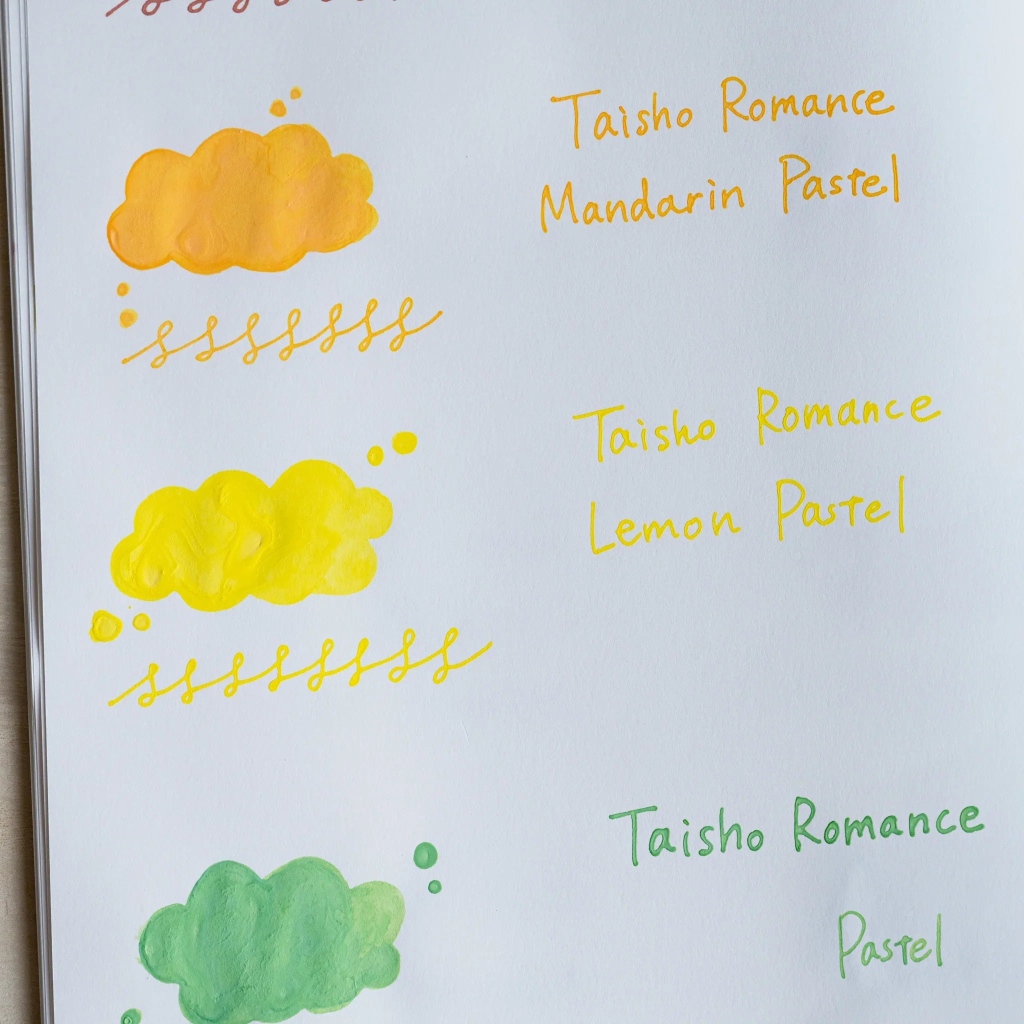 Handwritten swatch of Taisho Romance Lemon Pastel ink, a cloud-shaped wash and a looped line in yellow