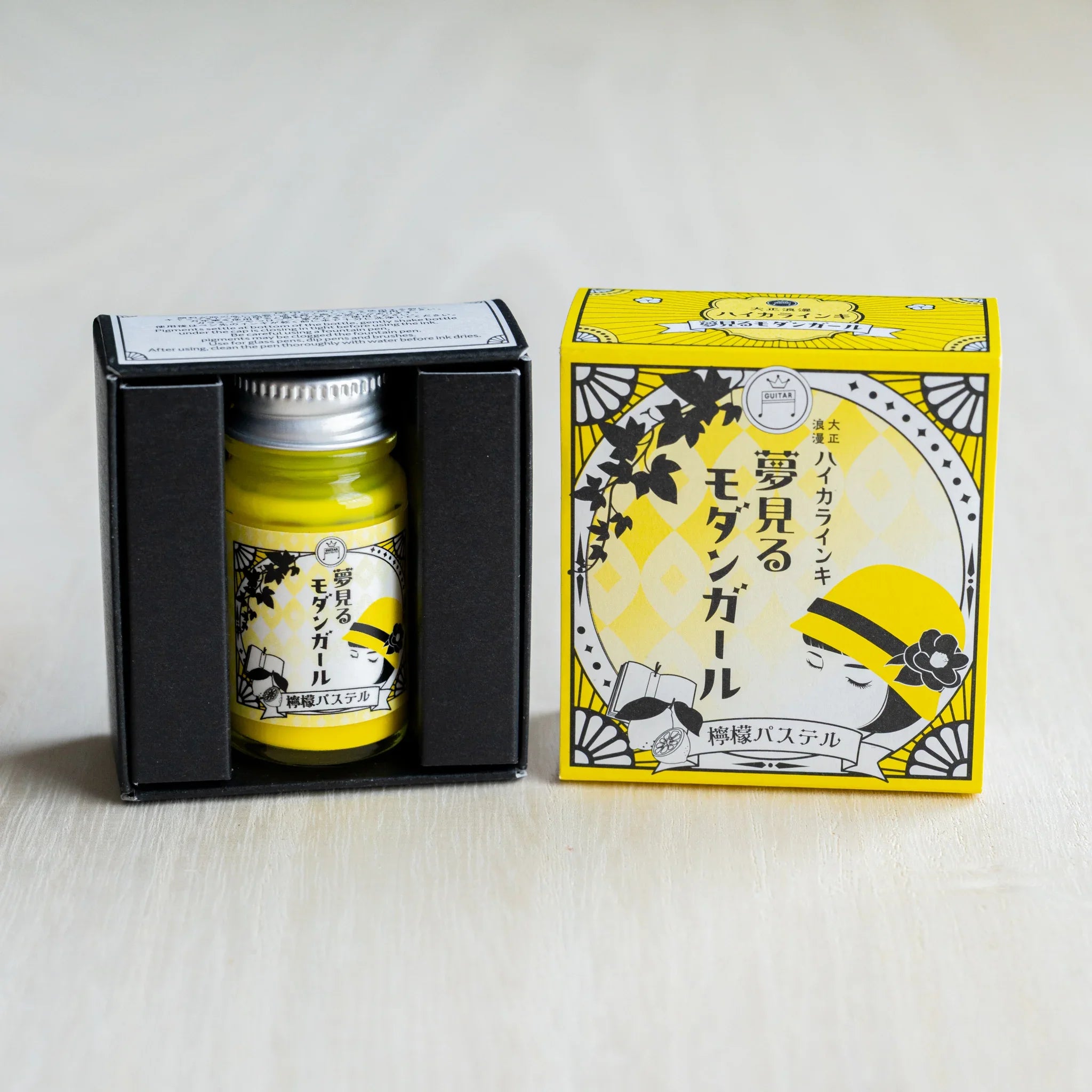 Taisho Romance Lemon Pastel ink bottle in its open black inner box, next to the closed bright yellow outer box