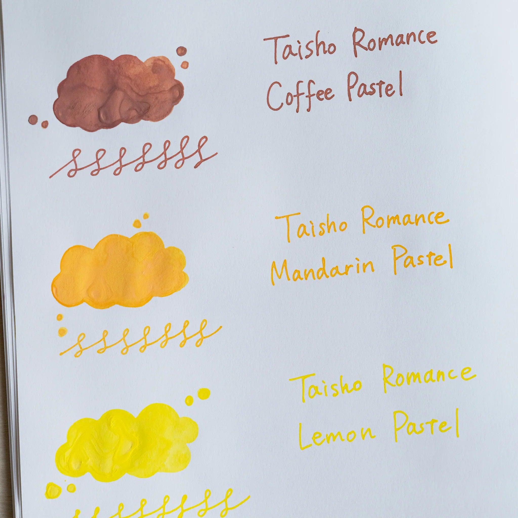 Handwritten swatch of Taisho Romance Mandarin Pastel ink, a cloud-shaped wash and a looped line in orange
