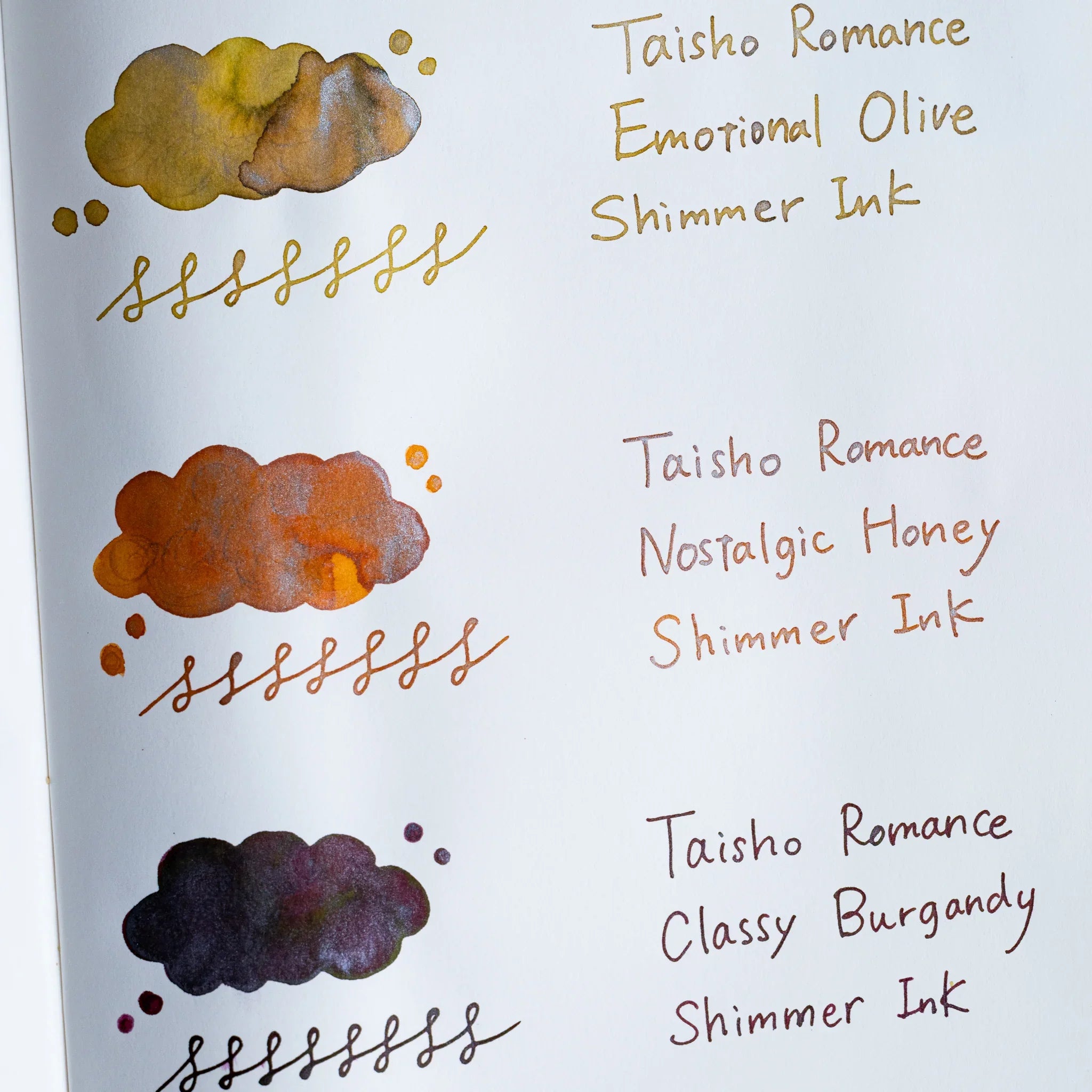 Handwritten swatch of Taisho Romance Nostalgic Honey Shimmer Ink, a cloud-shaped wash and looped line with silver flecks