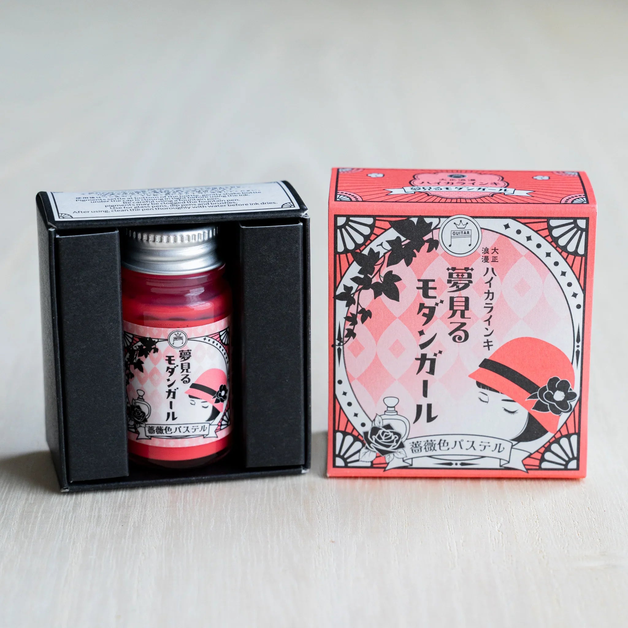 Taisho Romance Rose Pastel ink bottle in its open black inner box, next to the closed coral pink outer box