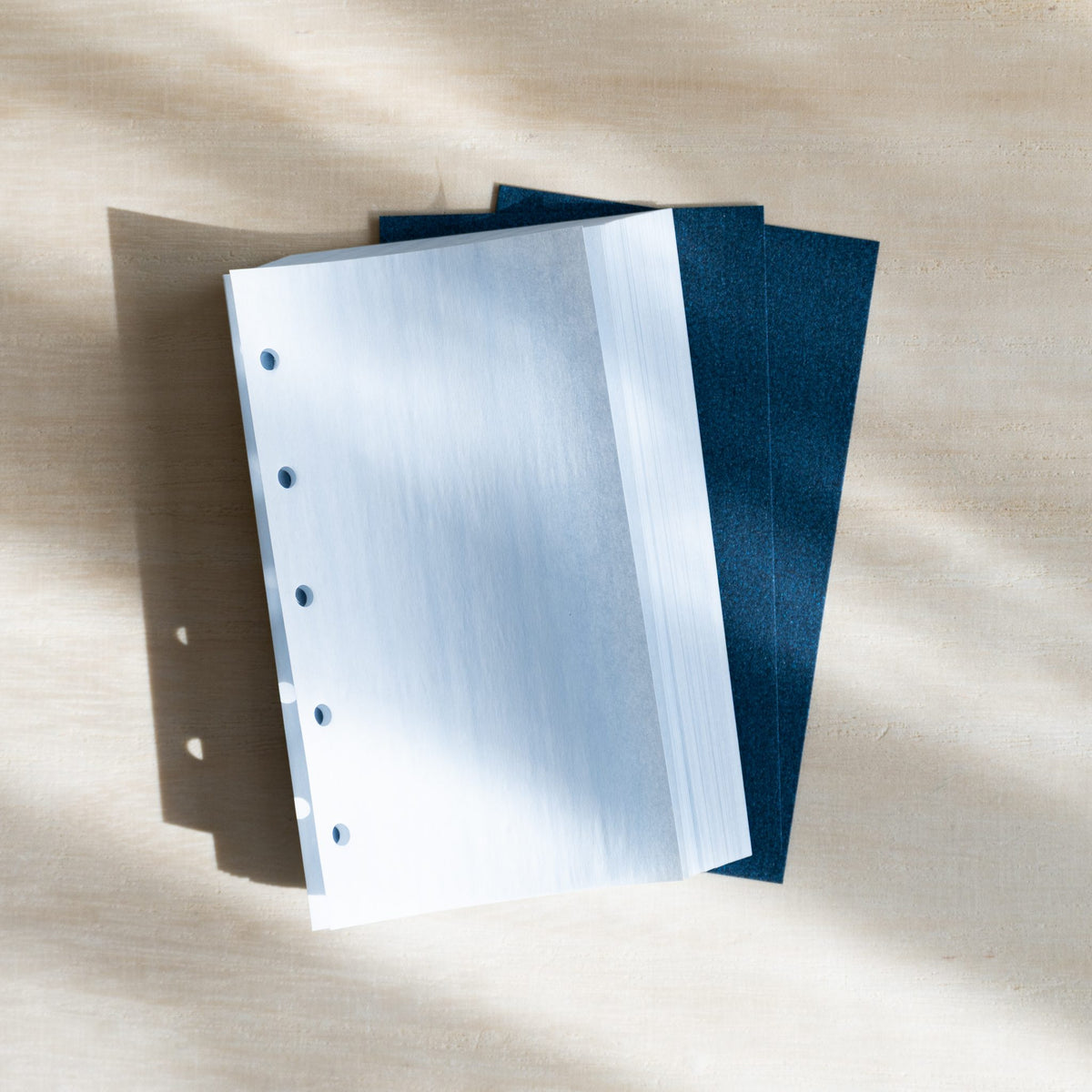 Pale blue KateJo Onion Skin M5 sheets fanned over two dark blue lifter sheets with punched holes