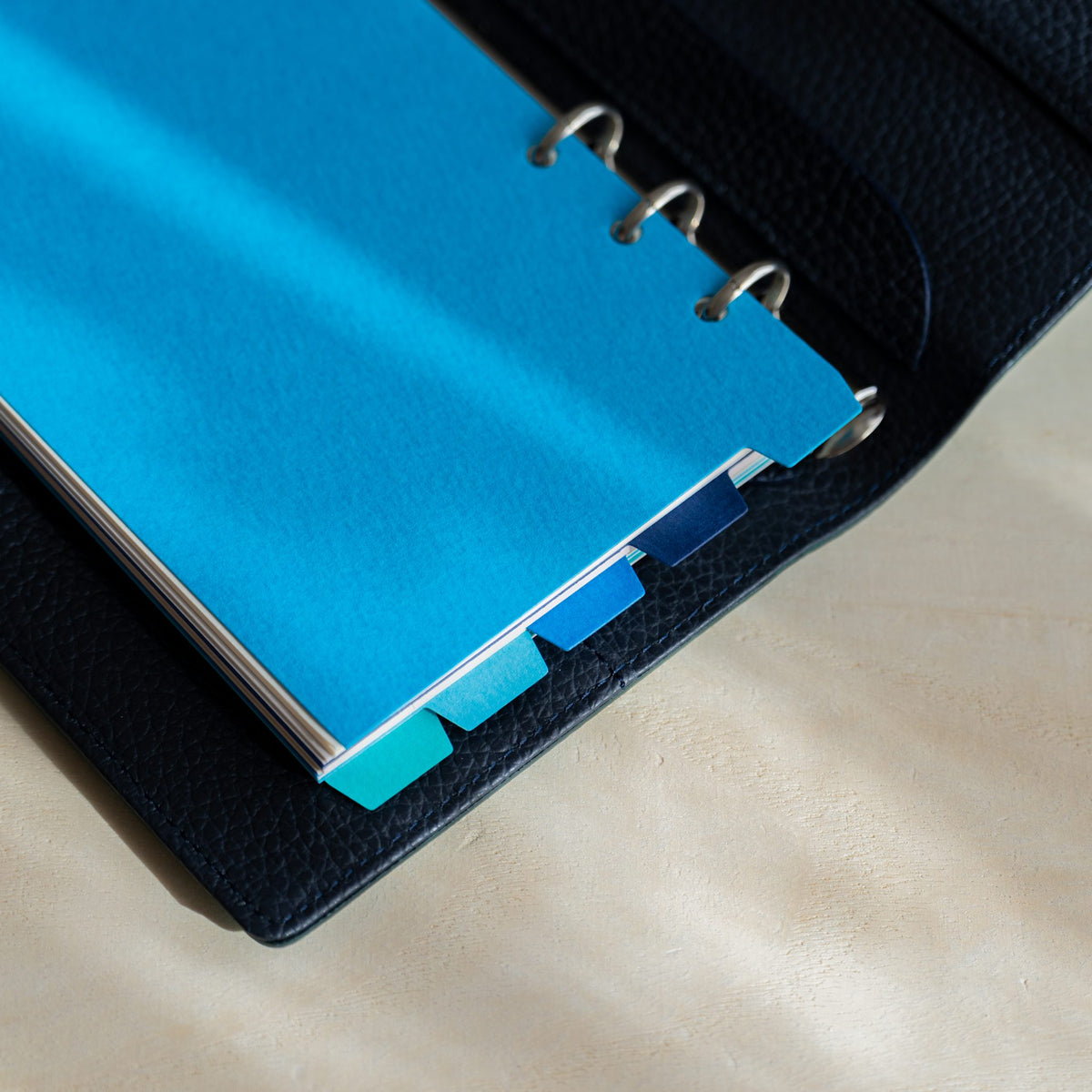 Mermaid Bible blue dividers in a navy planner with staggered blue and turquoise tabs at the edge