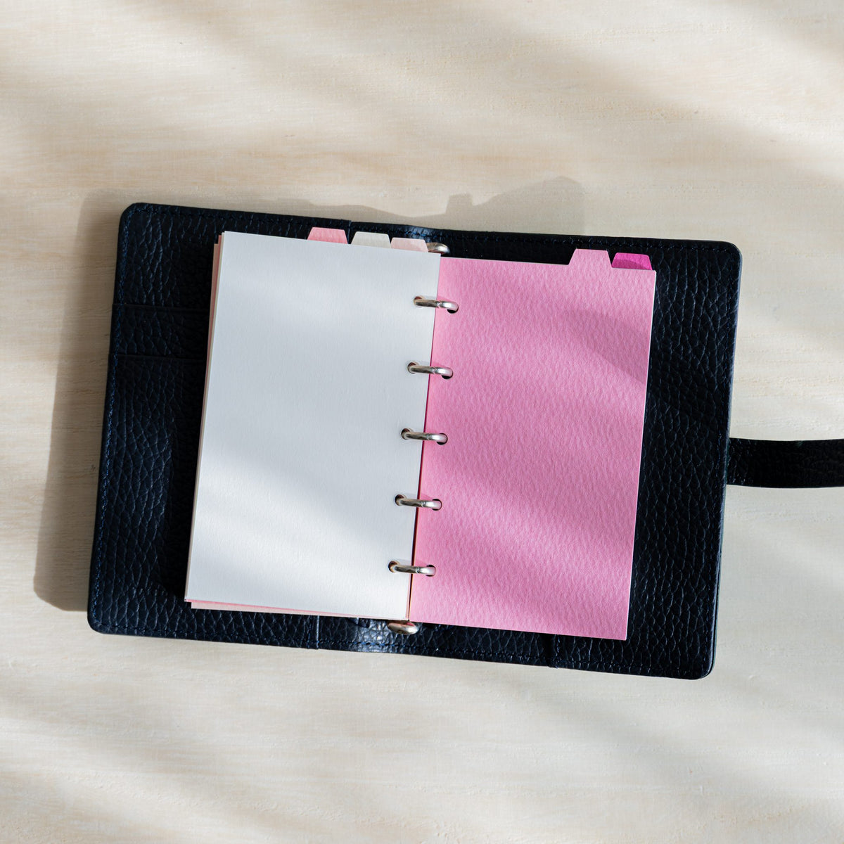 Open navy planner with a white page and a rose Mermaid M5 divider with top tab