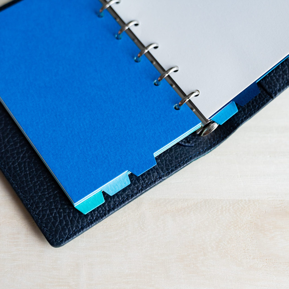 Cobalt Mermaid Mini 6 divider opposite a white page, blue and turquoise tabs at the edge