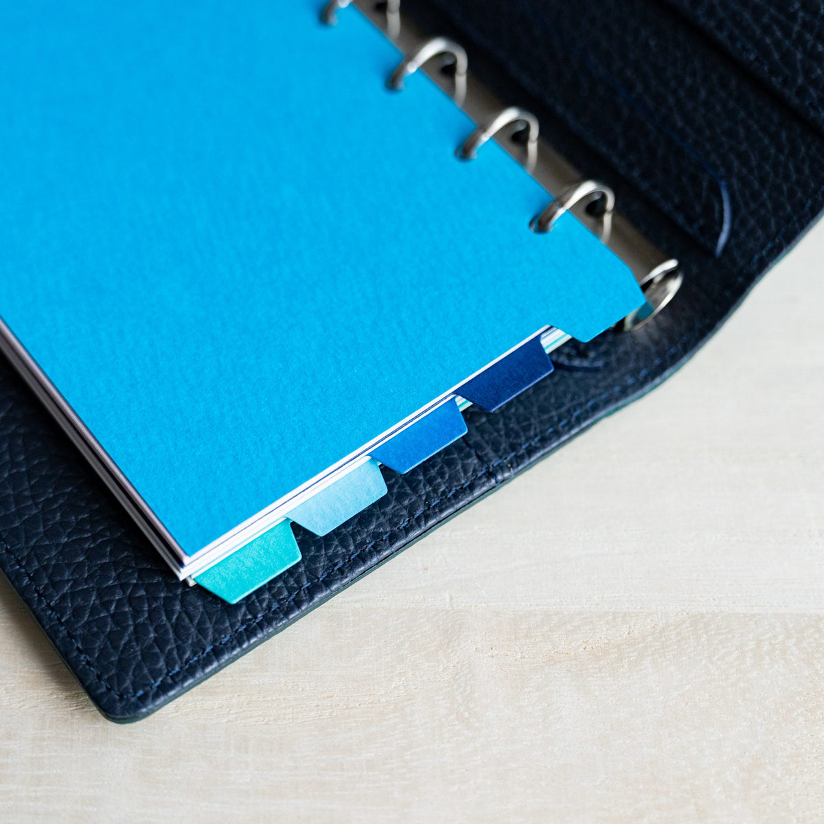 Mermaid Mini 6 blue dividers in a navy planner with staggered tabs along the edge