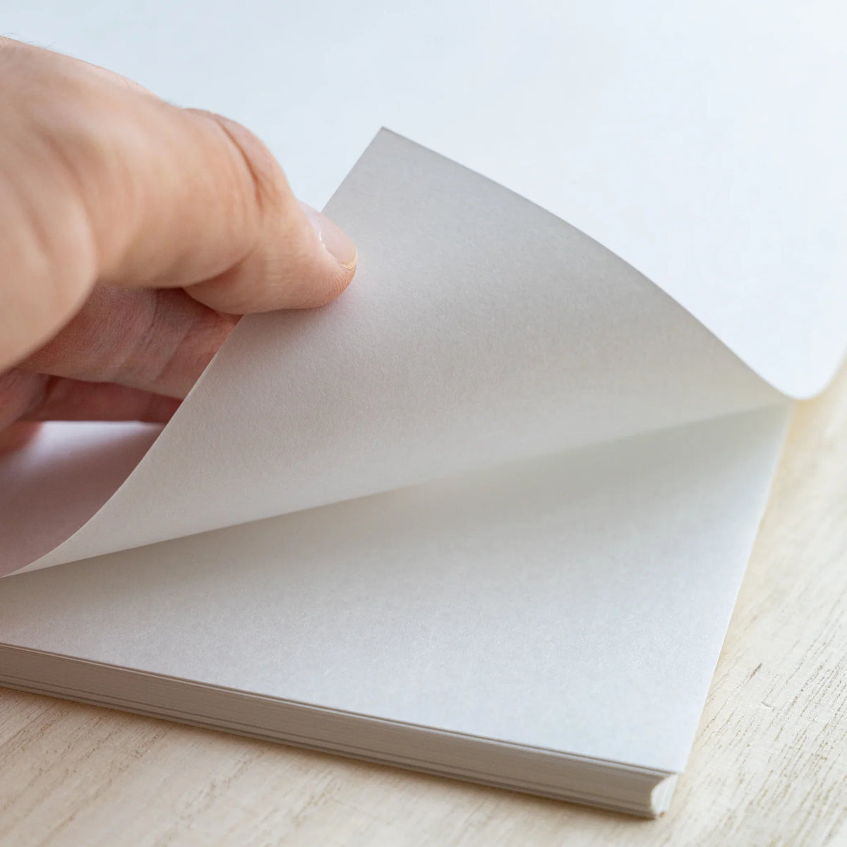 Hand lifting one blank sheet from the stack of Tateyama A4 loose leaf paper