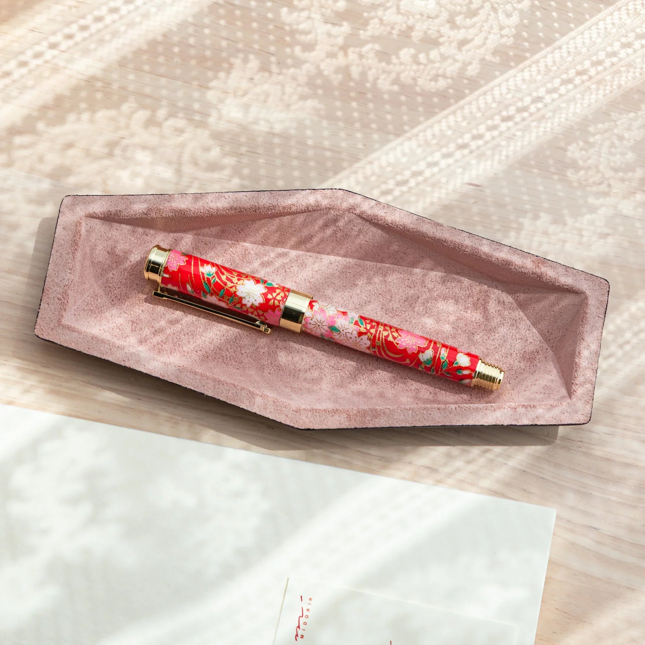 Slim Japanese Pen Tray made of blush pink suede and leather, shown empty in soft natural light from above.
