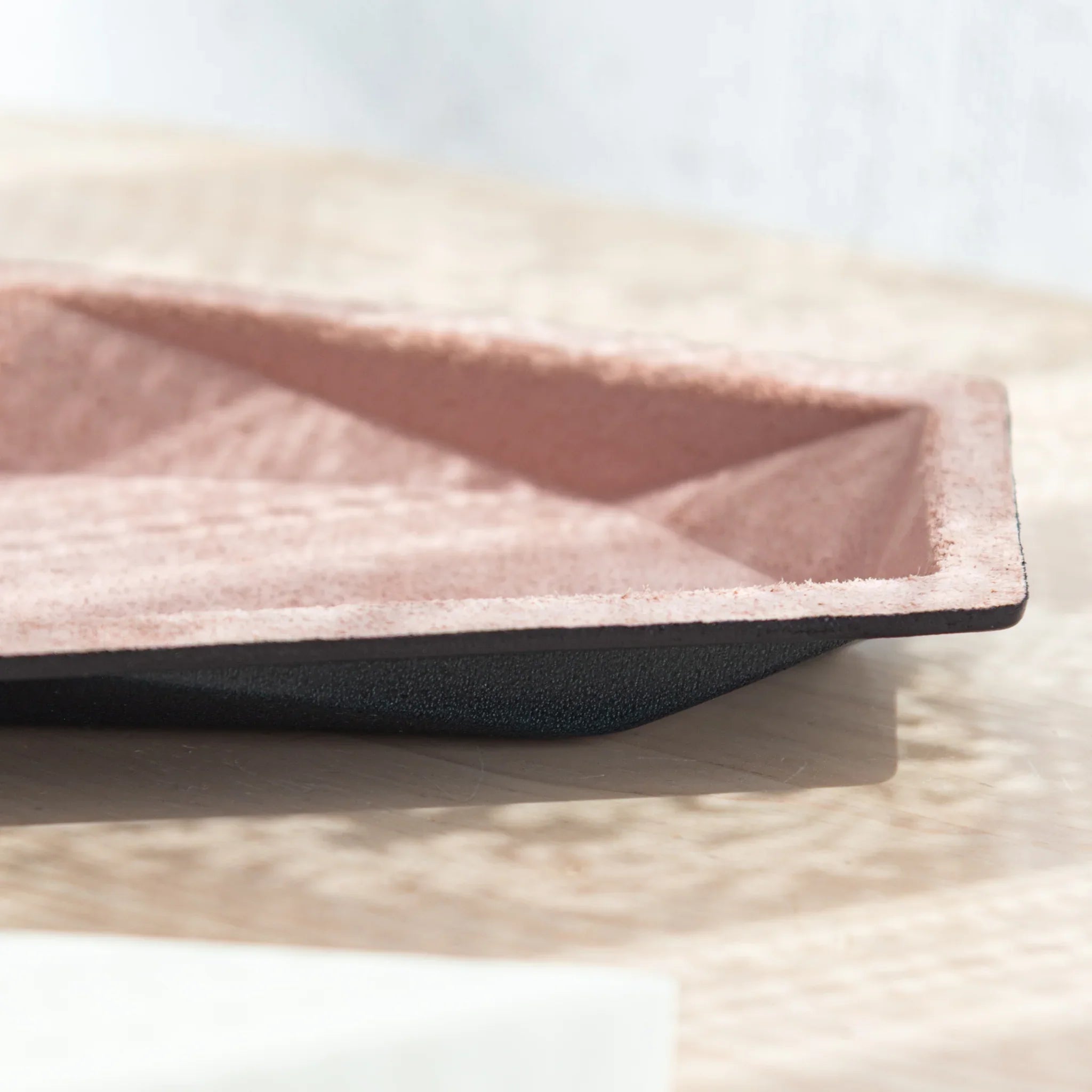 Side view of the slim Japanese Pen Tray showing textured pink suede and black leather base.
