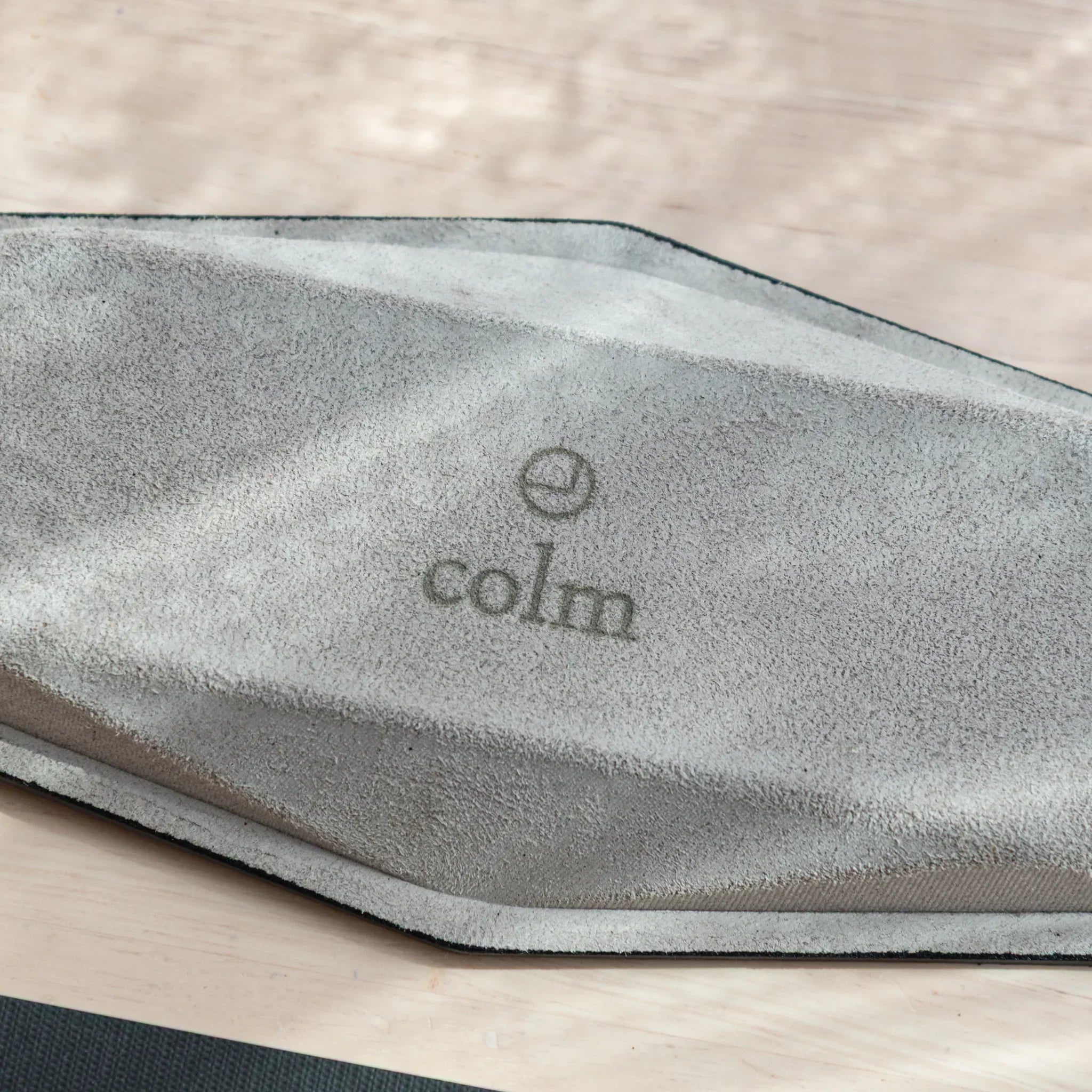 Close-up of colm logo on Teal-Blue suede base of Japanese Pen Tray.
