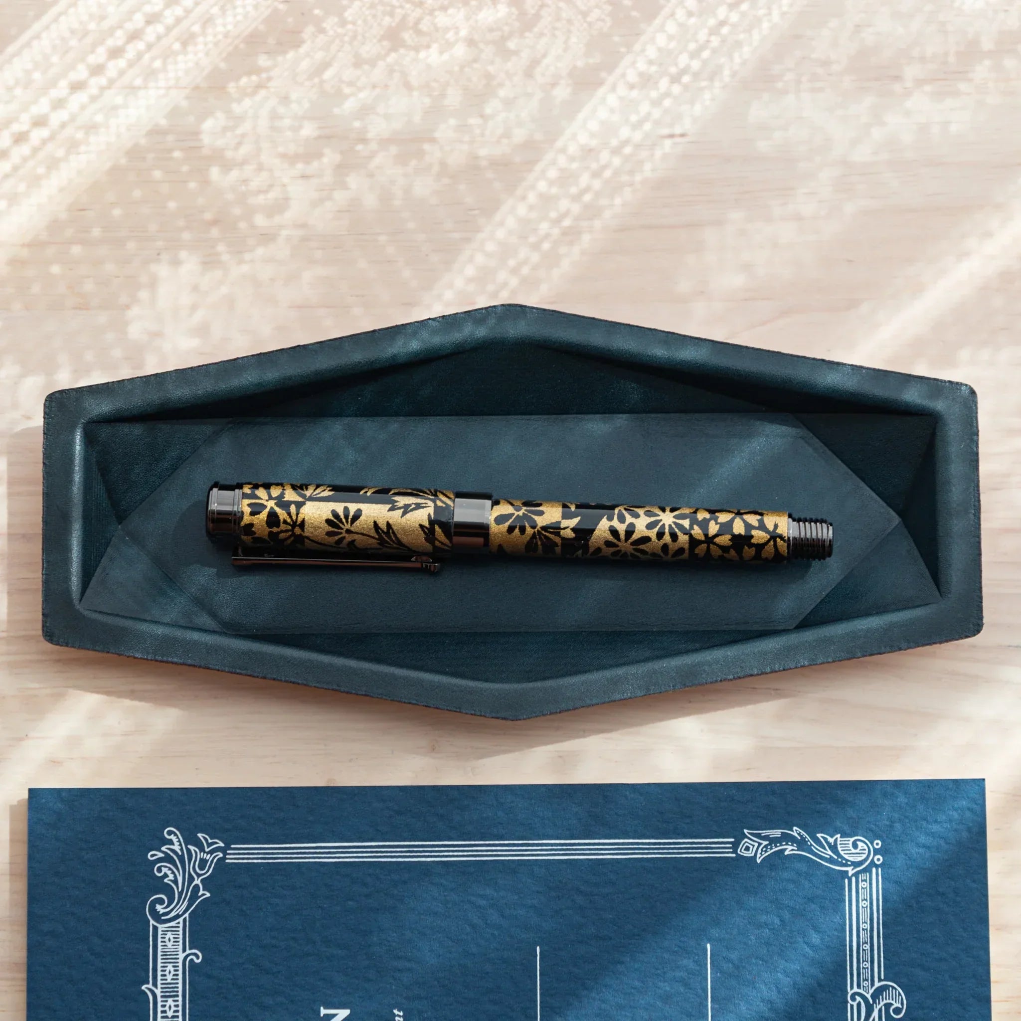 Japanese Fountain Pen with gold sakura pattern resting in Teal-Blue Japanese Pen Tray.