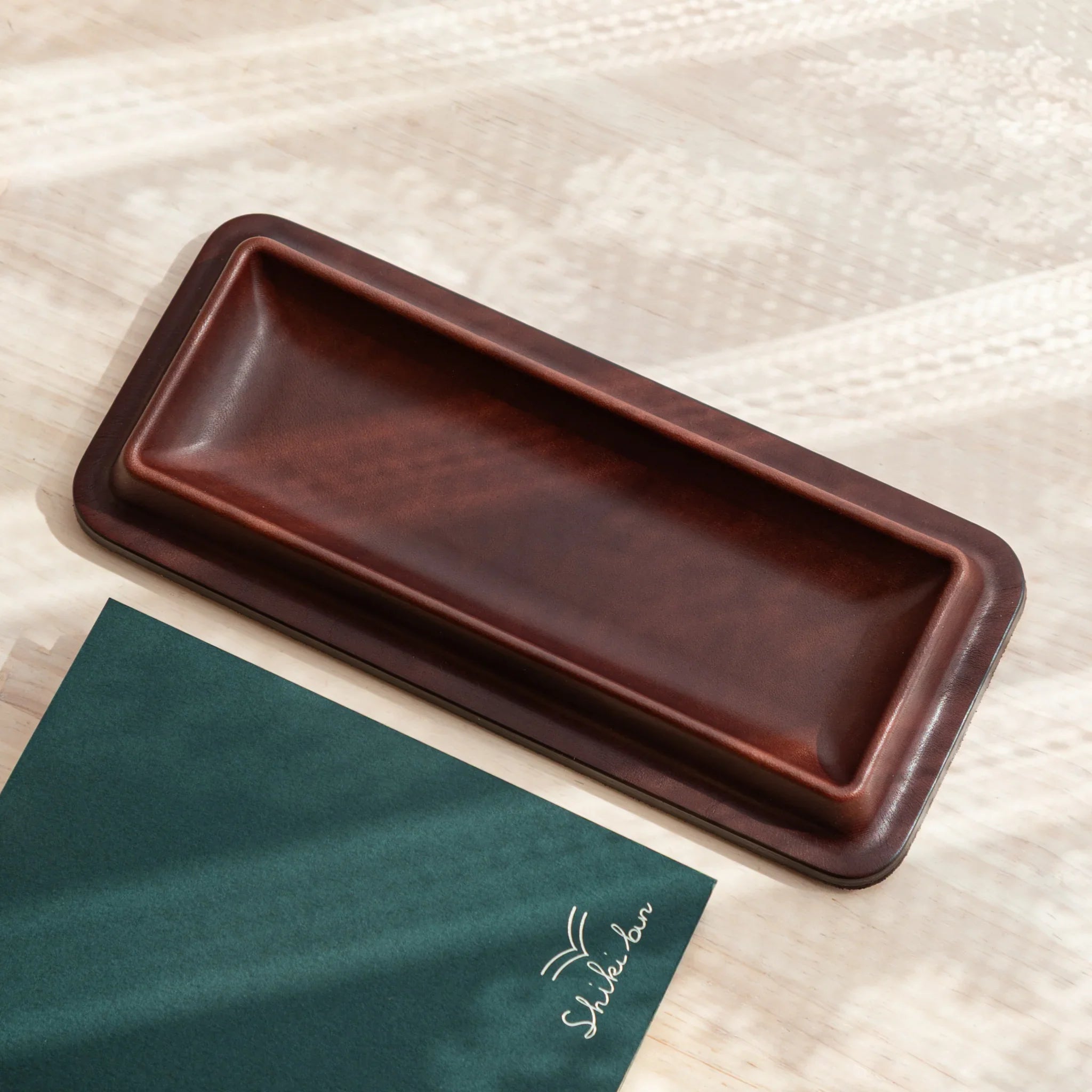 Japanese pen tray made of dark brown leather with a slim rectangular silhouette.