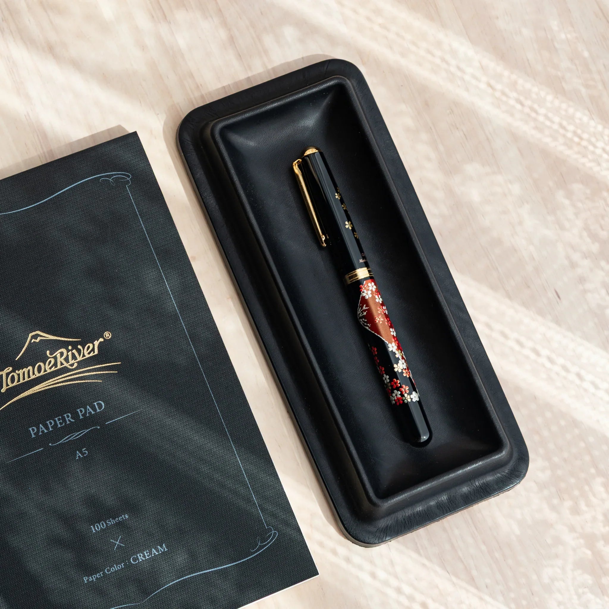 Tatsuno Leather Pen Tray Slim in black with a Japanese Fountain Pen, shown next to Tomoe River Paper Pad.