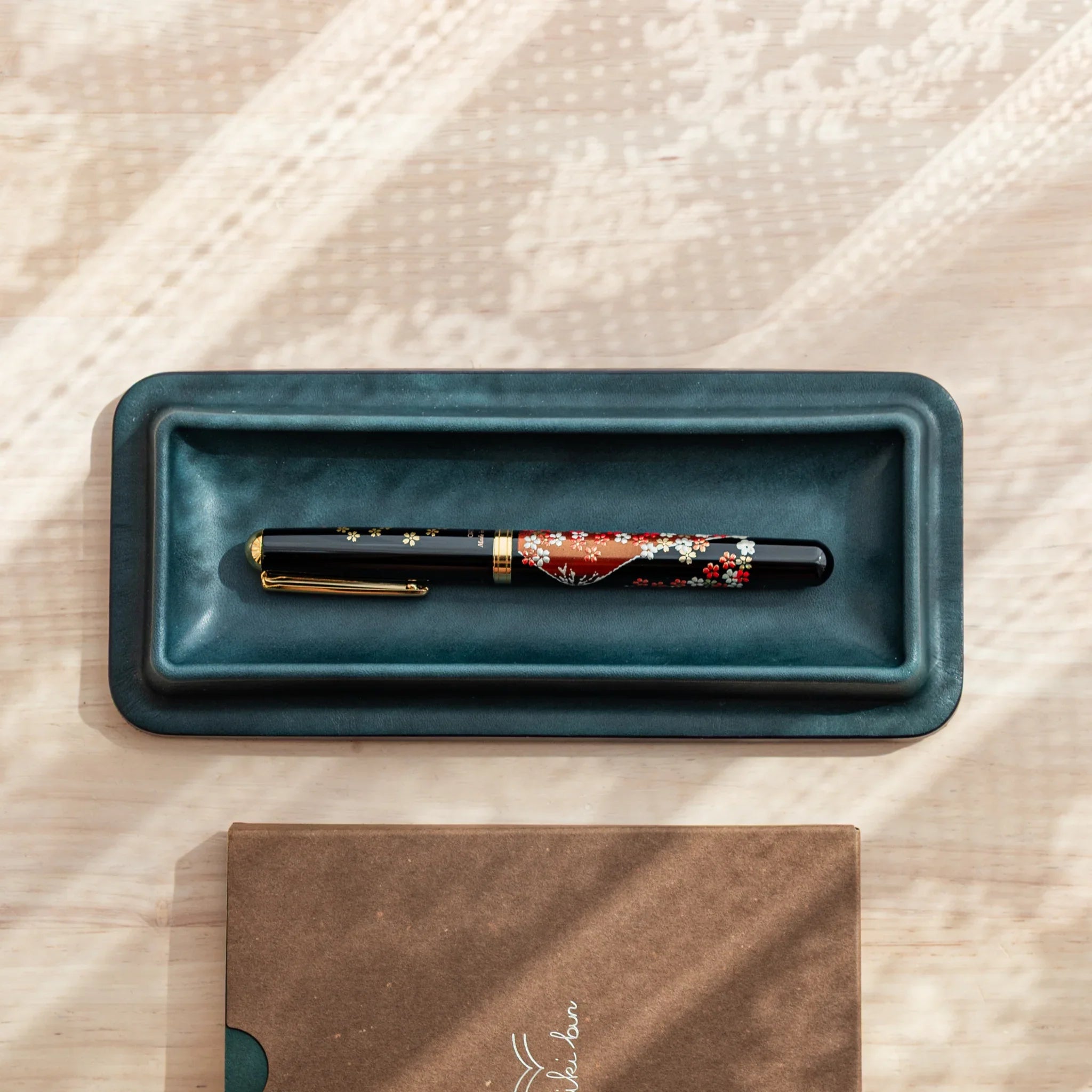 Japanese Fountain Pen placed horizontally in the center of the dark green Tatsuno Leather Pen Tray Slim.