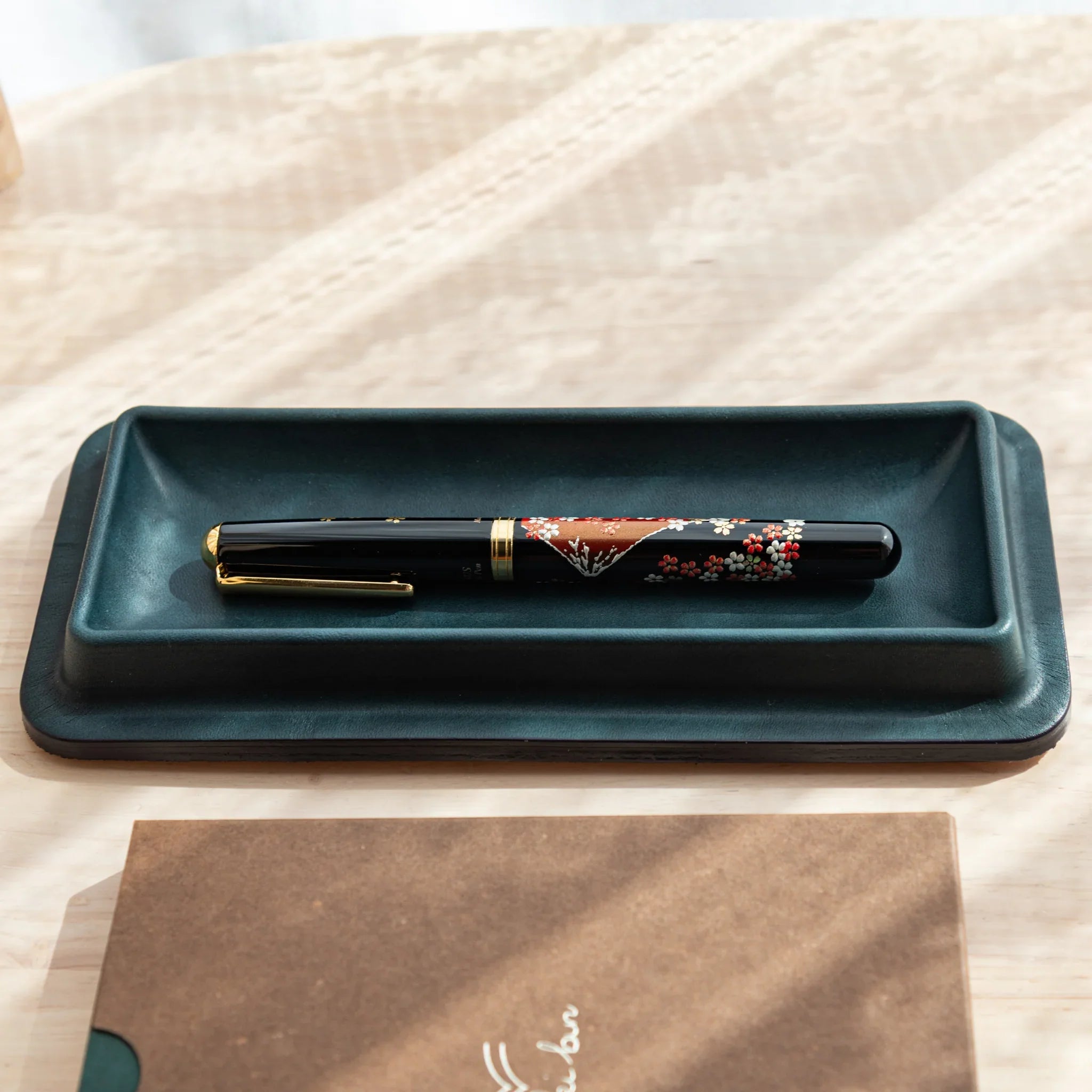 Side view of Japanese Fountain Pen resting in a dark green Tatsuno Leather Pen Tray Slim.