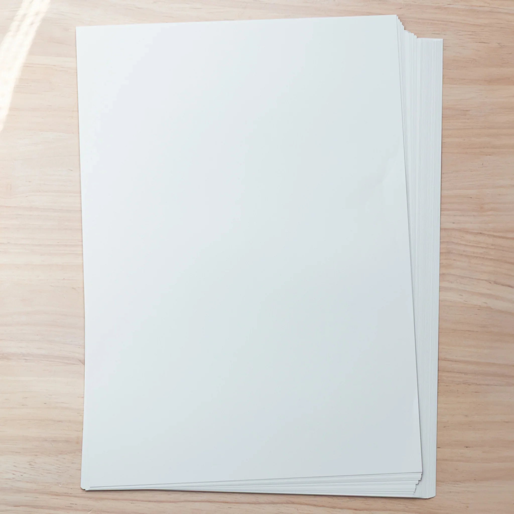 Stack of Tomoe River Japanese Loose Leaf Paper A4, 52gsm lightweight sheets displayed on wooden desk.