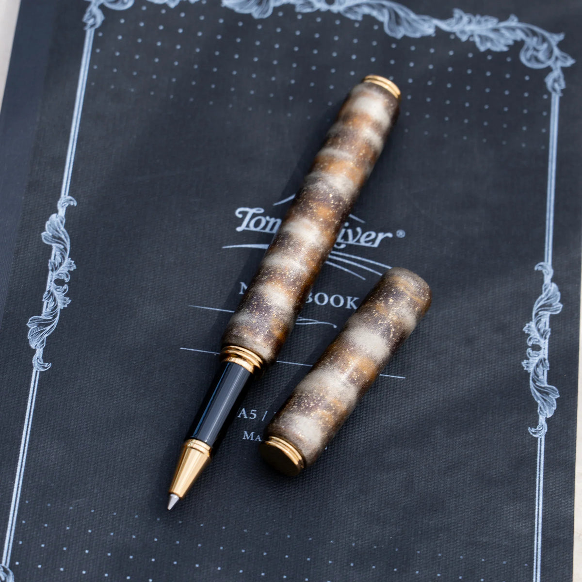Translucent brown marbled urushi lacquered rollerball pen in zelkova wood with the cap removed, showing the barrel and gold trim