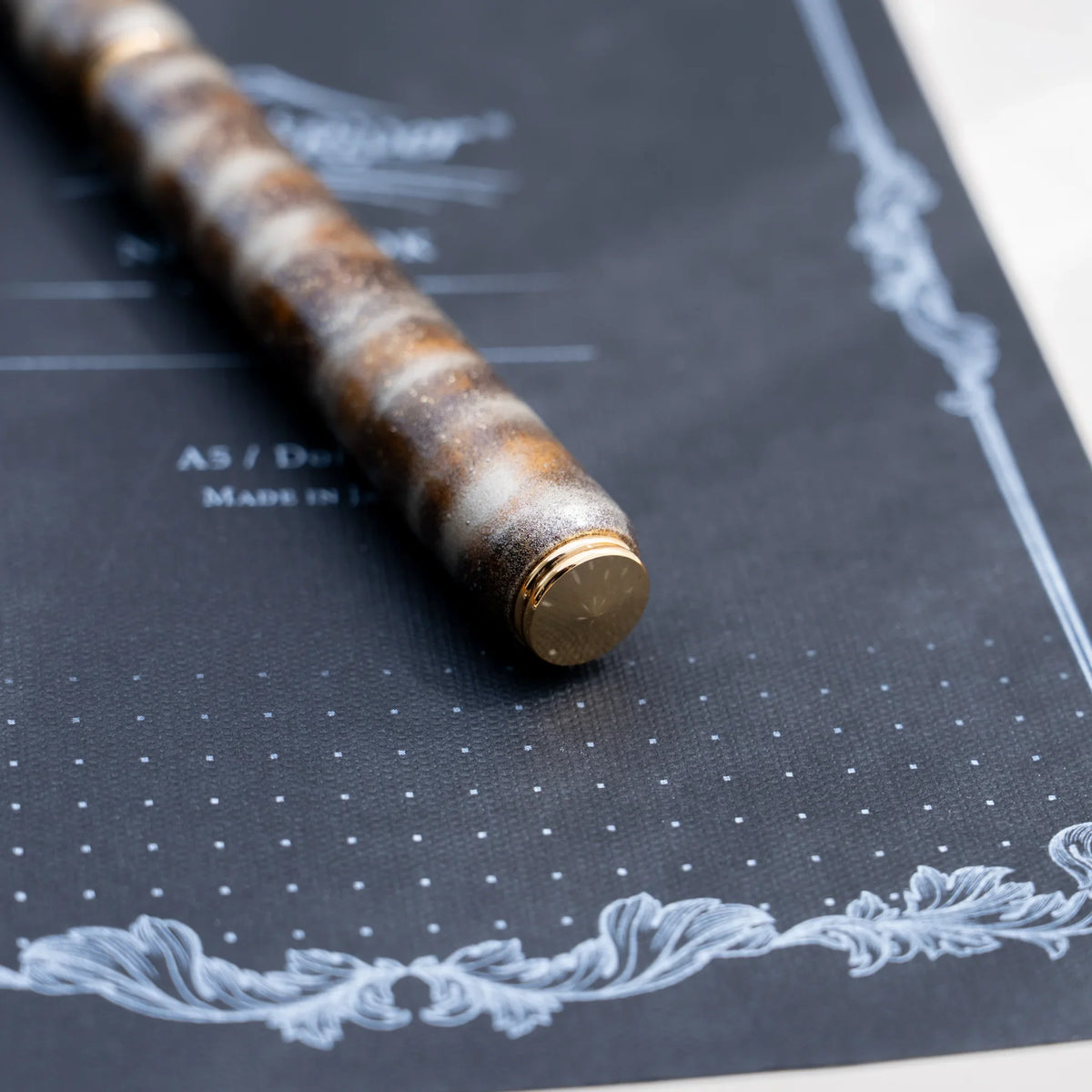 Detail of the layered color urushi and tin powder finish on the translucent brown pen