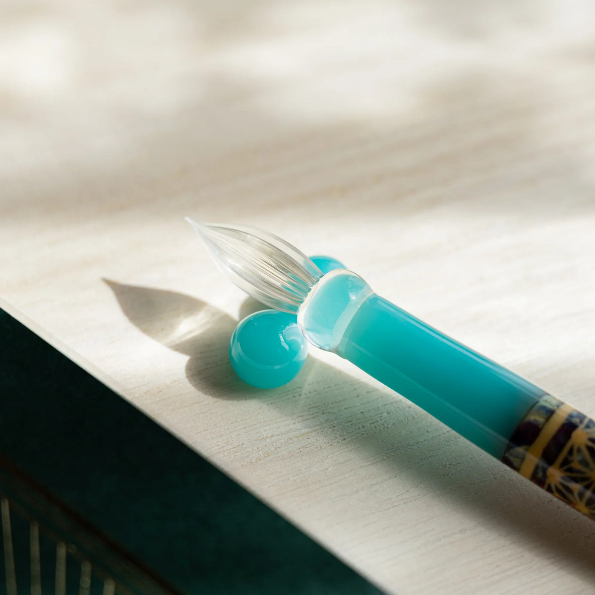 Turquoise Hemp Leaves glass dip pen nib and two-sphere turquoise pen rest on pale wood