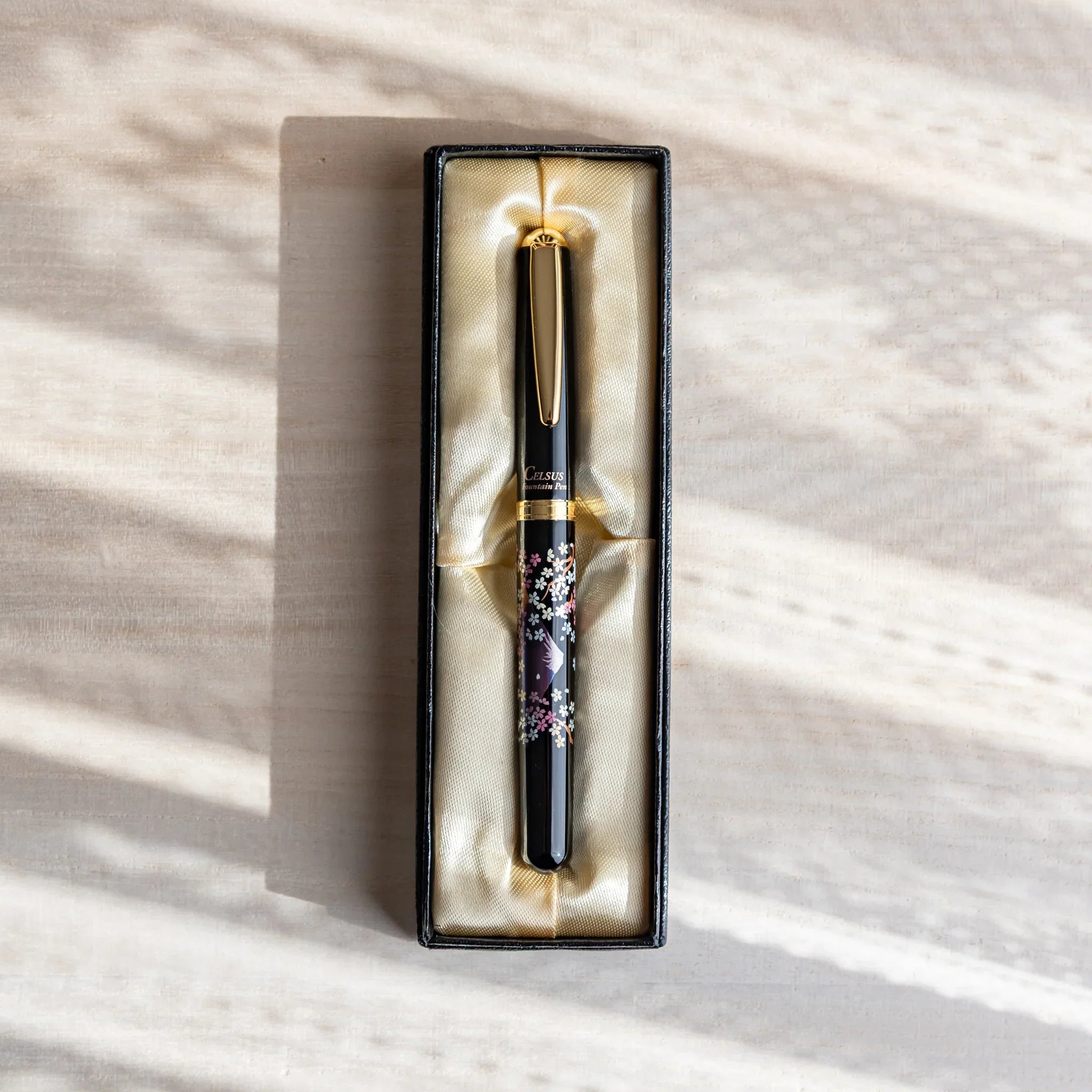 Japanese Fountain Pen featuring twilight Mt. Fuji and pink sakura artwork placed in a black gift box on a wooden desk.