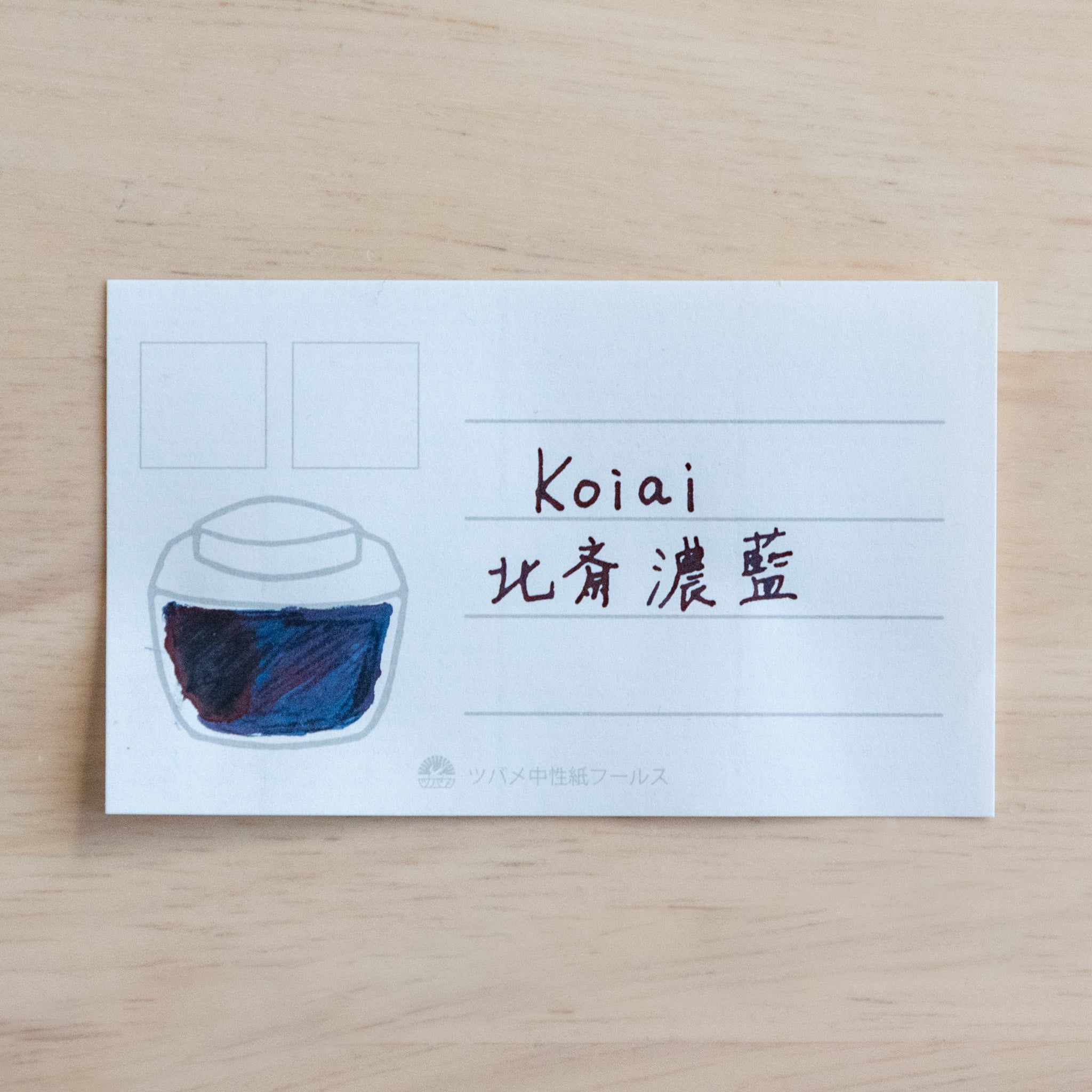 A swatch of "Koiai" ink on a card. The card features a jar illustration filled with deep blue ink and handwritten text in English and Japanese.