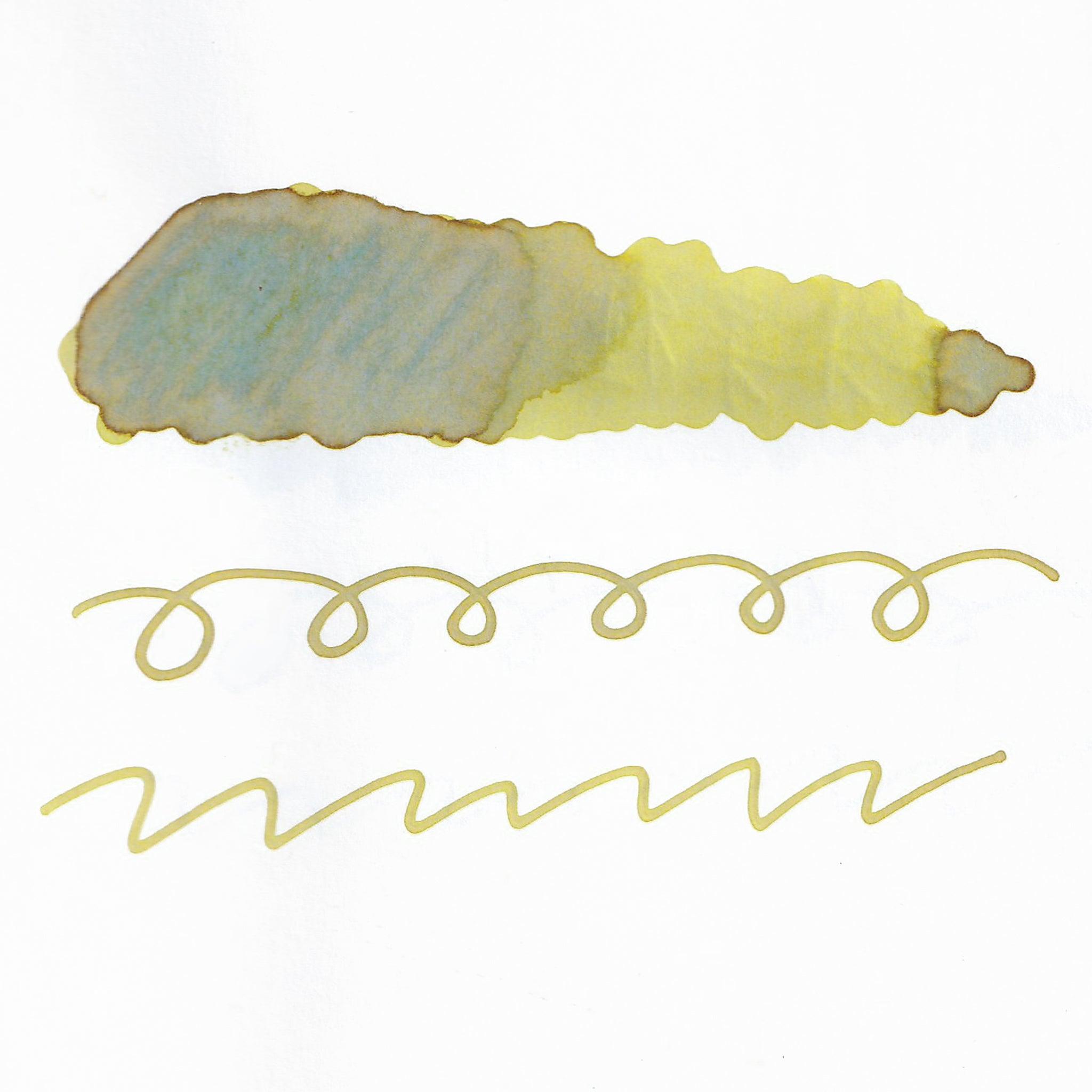 Swatch of yellow fountain pen ink on white paper. The ink shows shading variations, with a dark center and lighter edges. Below are wavy and looped lines demonstrating the ink's flow.  