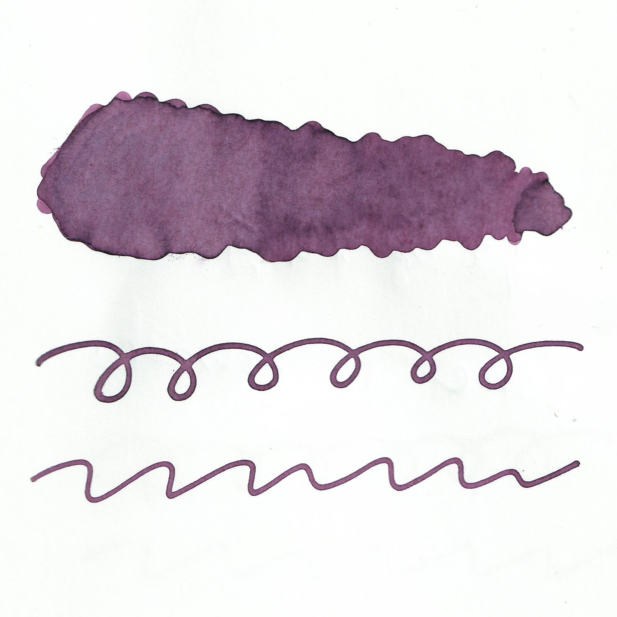 Swatch of purple fountain pen ink on white paper. The ink shows shading variations, with a darker center and lighter edges. Below the swatch, two sets of wavy and looped lines demonstrate the ink's flow.