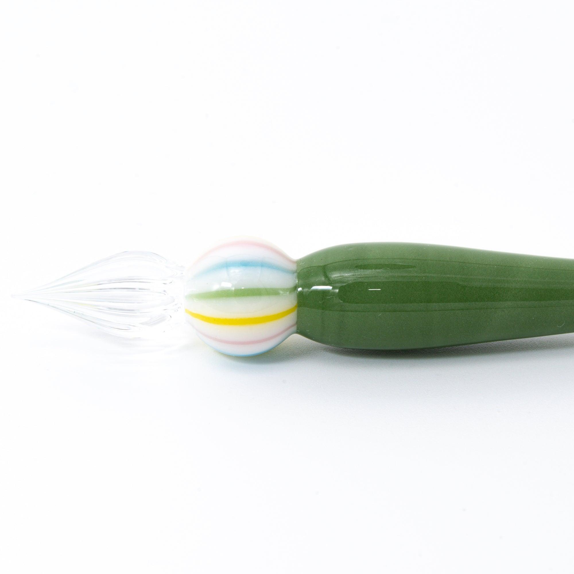 A close-up of a green matcha color glass pen with a colorful marble-like detail on both ends, resting on a clean, white background.