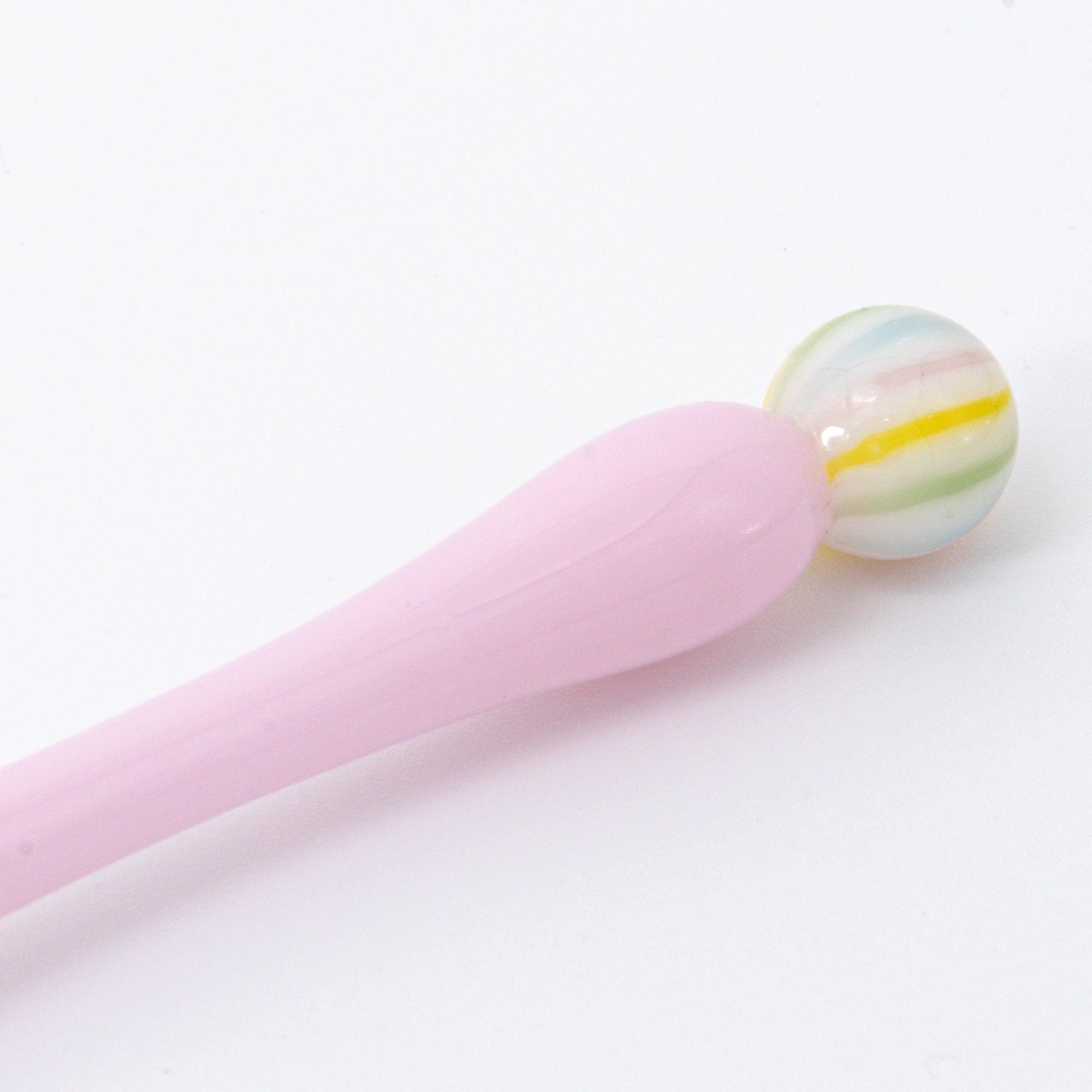 A pink glass pen inspired by traditional Japanese wagashi, featuring pastel-colored, marble-like glass beads at each end for a delicate and playful aesthetic.