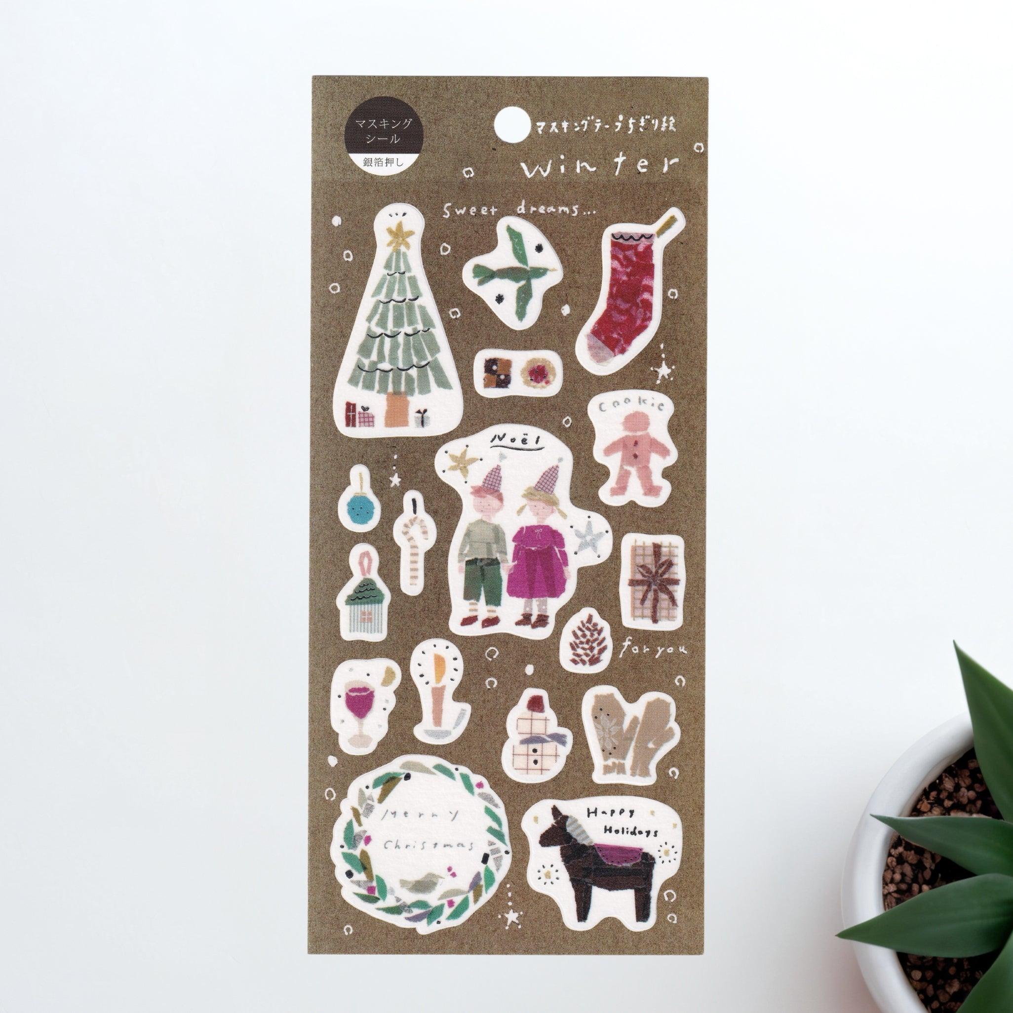 A Japanese stationery washi sticker sheet featuring winter-themed designs, including a Christmas tree, stockings, ornaments, festive treats, and holiday wreaths, in a cozy watercolor style.