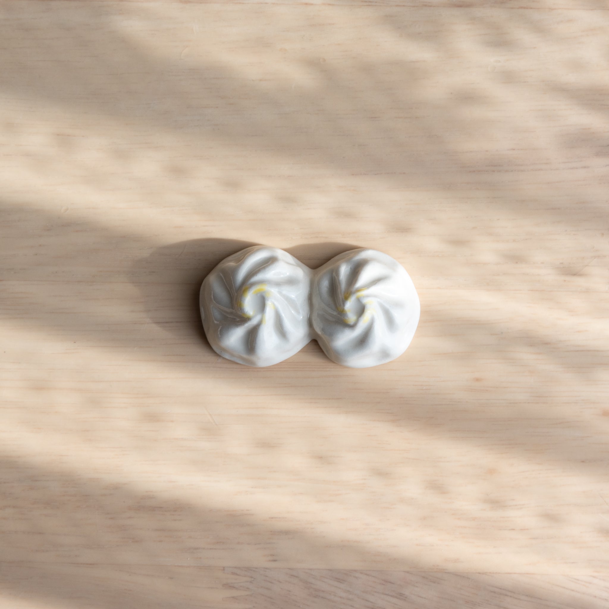 Two ceramic Xiaolongbao-shaped pen rests on a wooden surface.