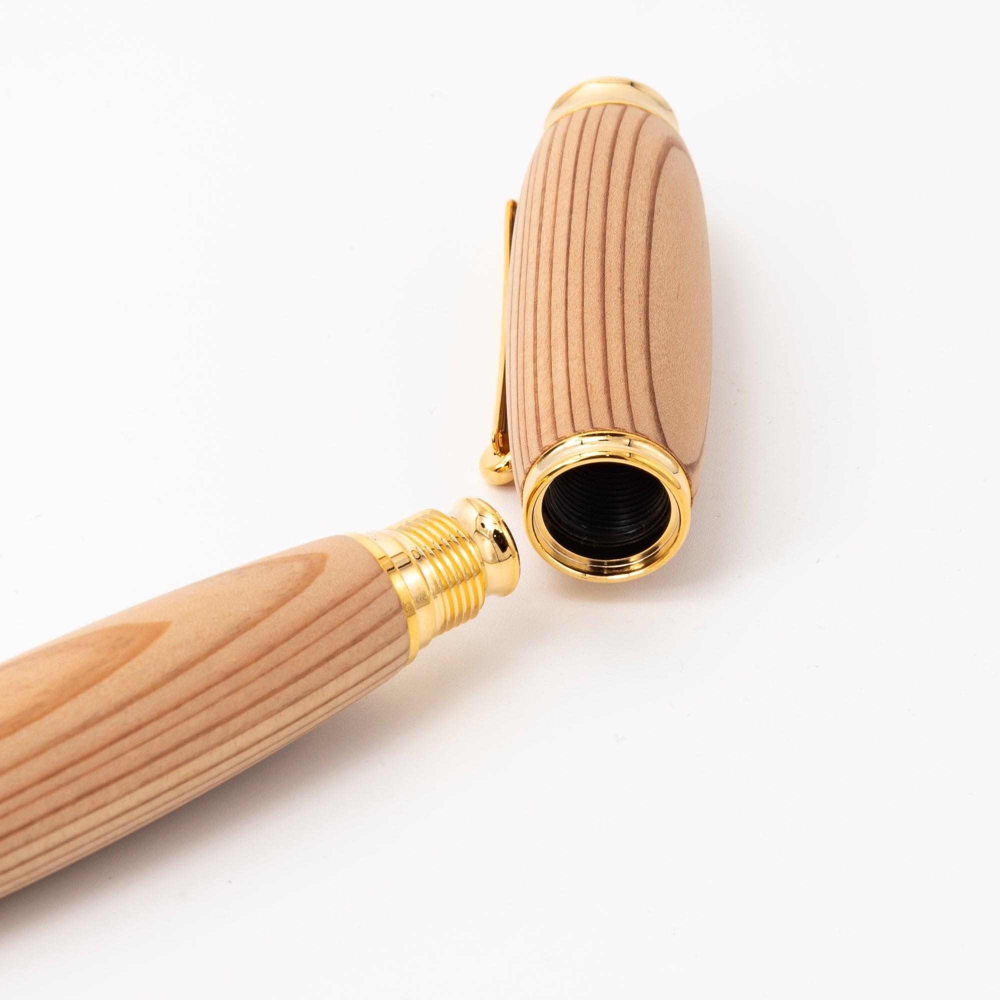 A close-up of a Japanese Yakushima cedar wood fountain pen showcasing its screw cap mechanism with gold details on a plain white background.