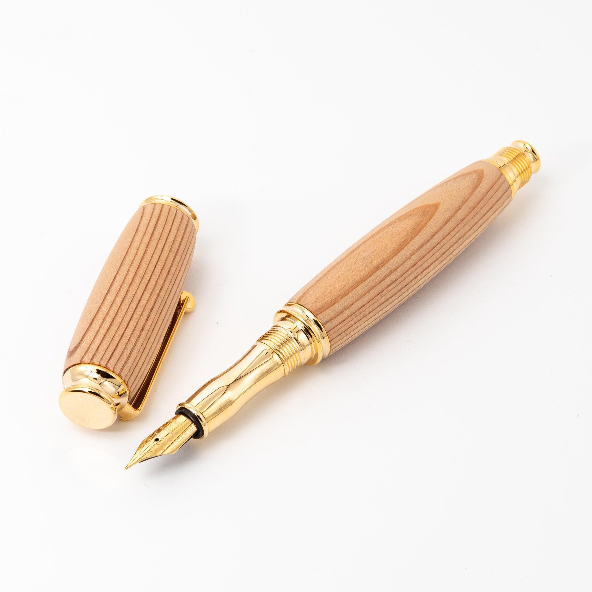 A Japanese Yakushima cedar wood fountain pen with gold accents, displayed open to showcase its luxurious nib and detachable cap on a clean white background.