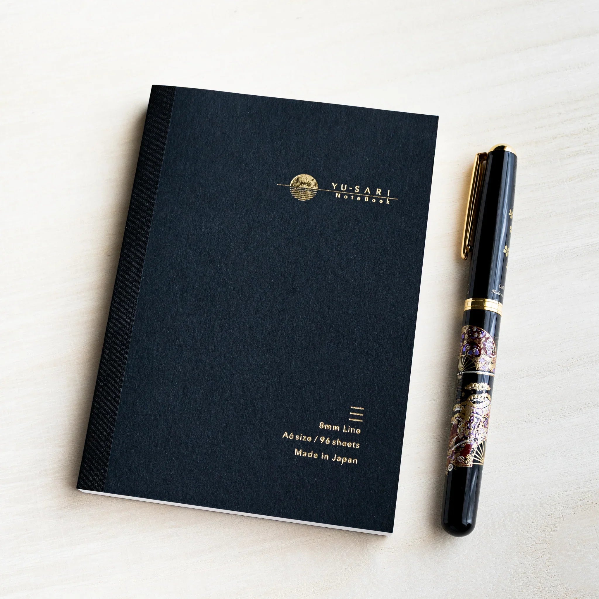 Black A6 YU-SARI lined notebook on wood beside a black lacquer maki-e fountain pen, gold 8mm Line, A6 size, 96 sheets text