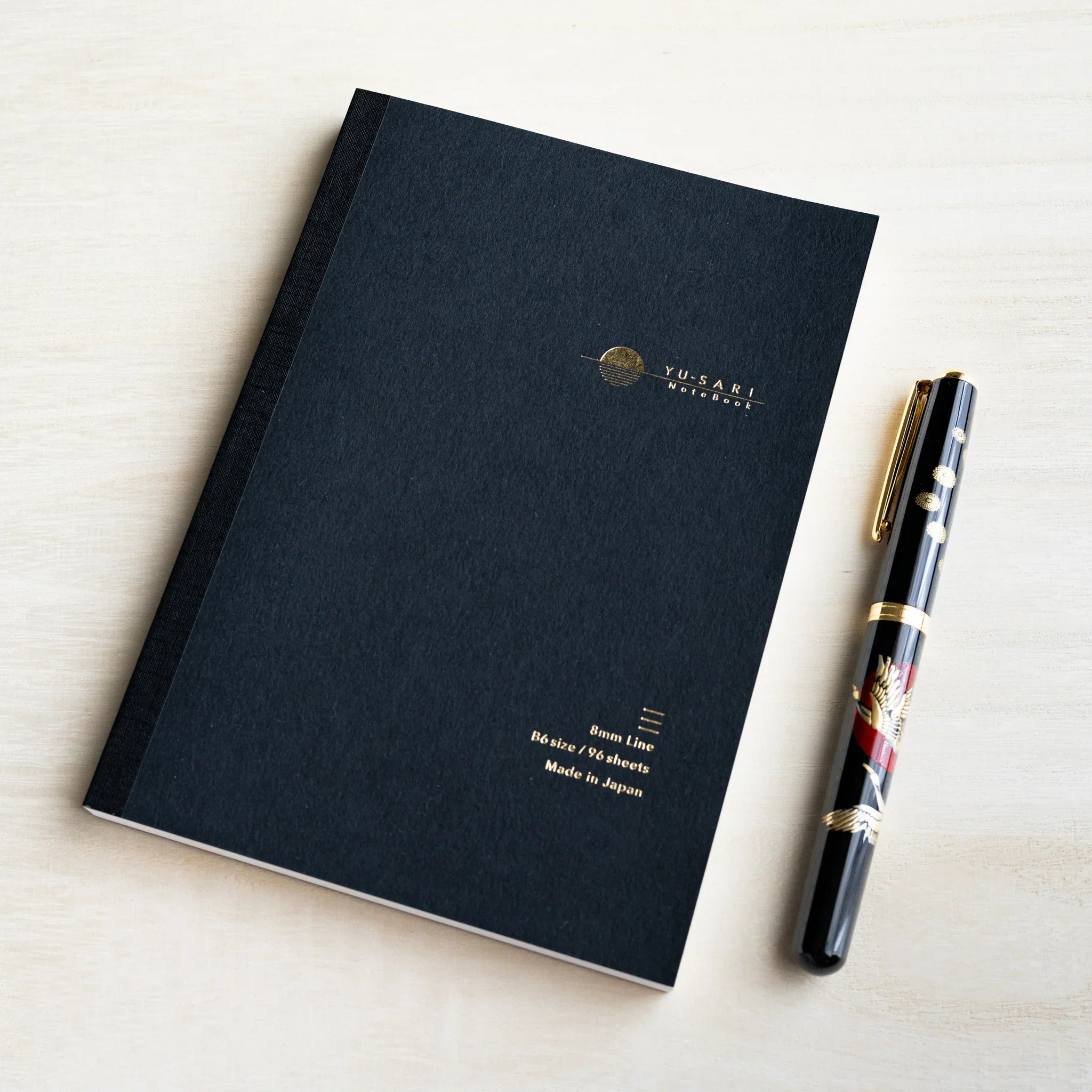 Black B6 YU-SARI lined notebook on wood beside a black lacquer maki-e fountain pen, gold 8mm Line, B6 size, 96 sheets text