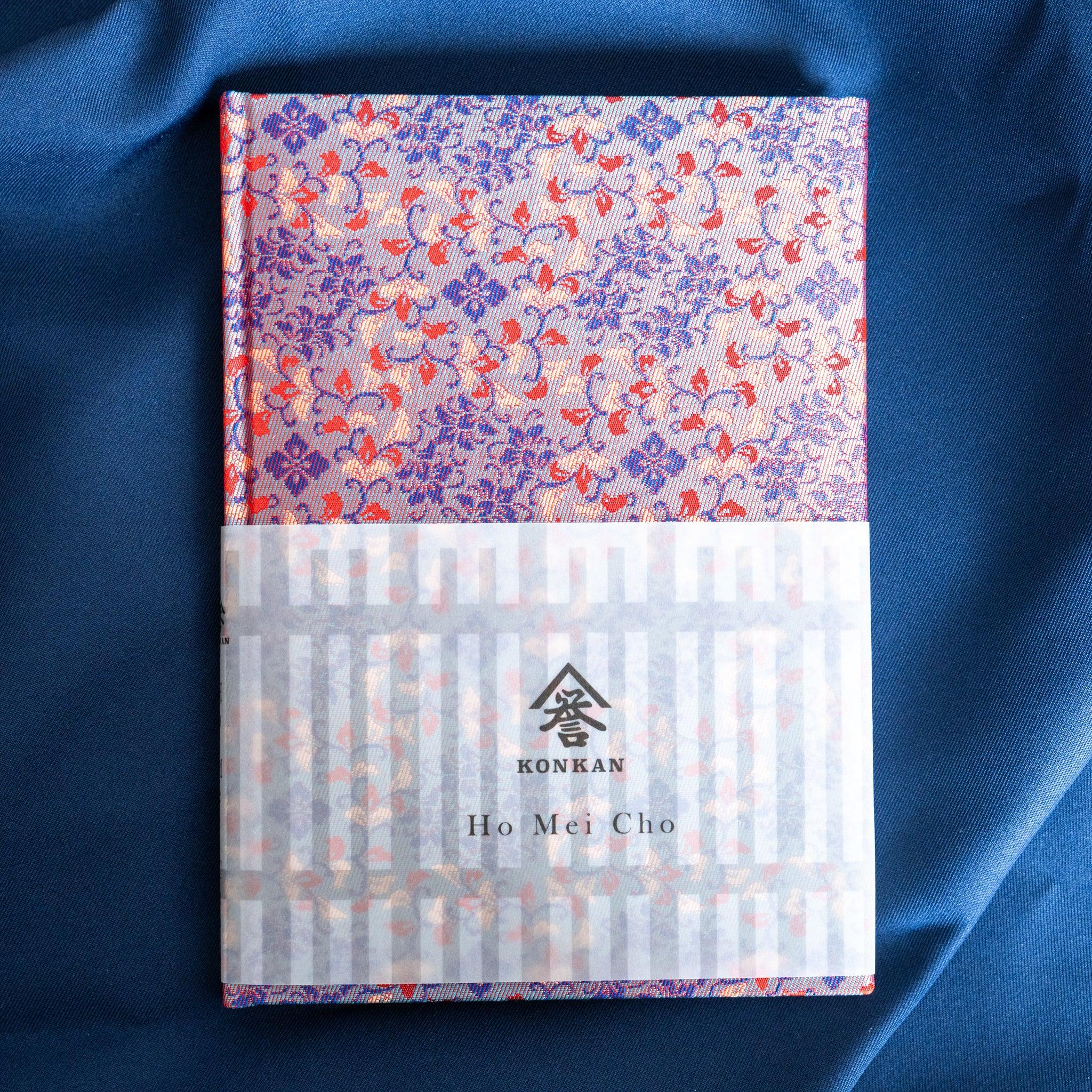 Yusoku Hanabishi Nishijin silk notebook, blue and red floral woven cover, paper belly band with KONKAN logo and Ho Mei Cho