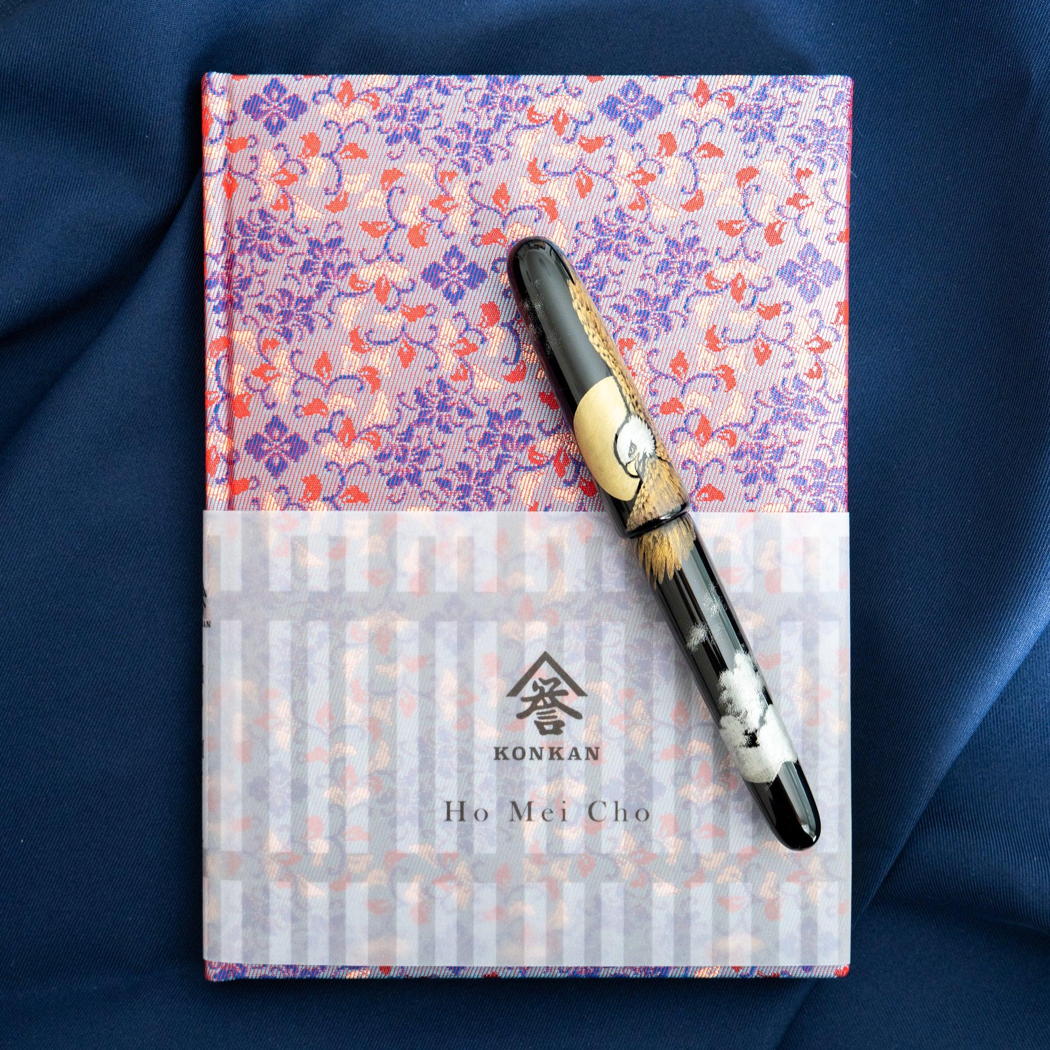 Yusoku Hanabishi Nishijin silk notebook, blue and red floral woven cover, fountain pen resting on top, belly band with KONKAN