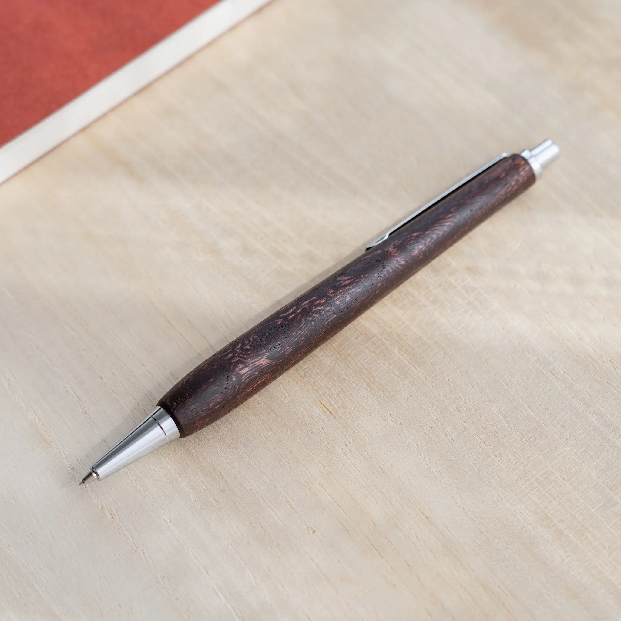 Dark reddish-brown zelkova wood urushi mechanical pencil, close-up of silver cone tip and lead, Japanese keyaki
