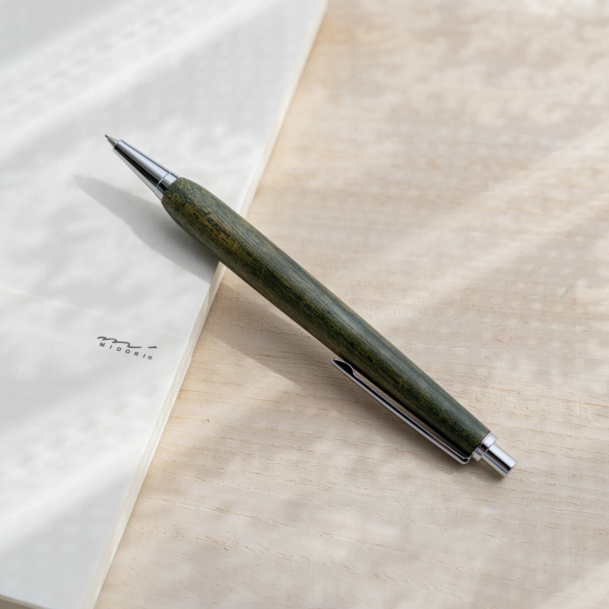 Olive green zelkova wood urushi mechanical pencil, close-up of barrel wood grain and silver clip, Japanese keyaki