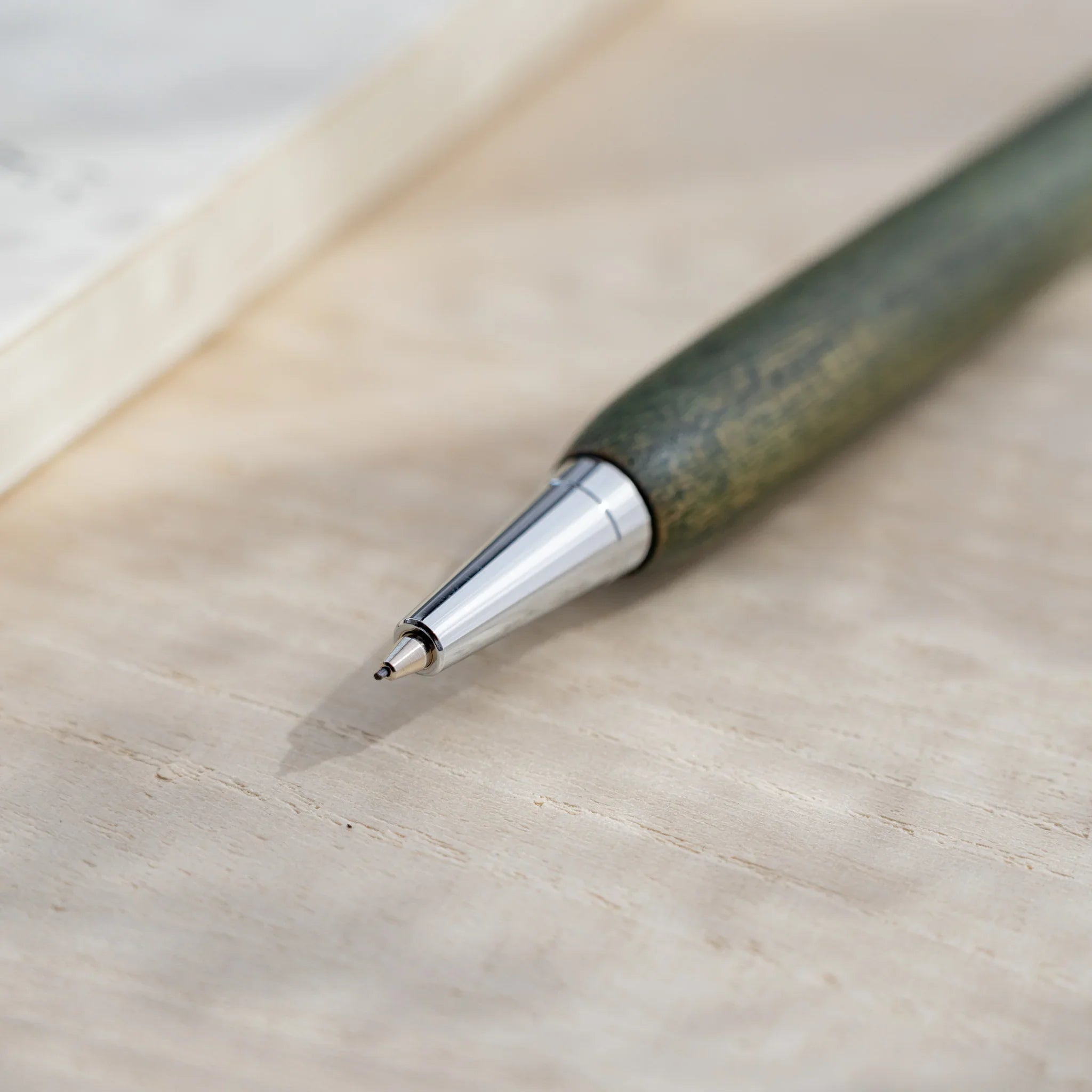 Olive green zelkova wood urushi mechanical pencil, close-up of silver cone tip and lead, Japanese keyaki wood