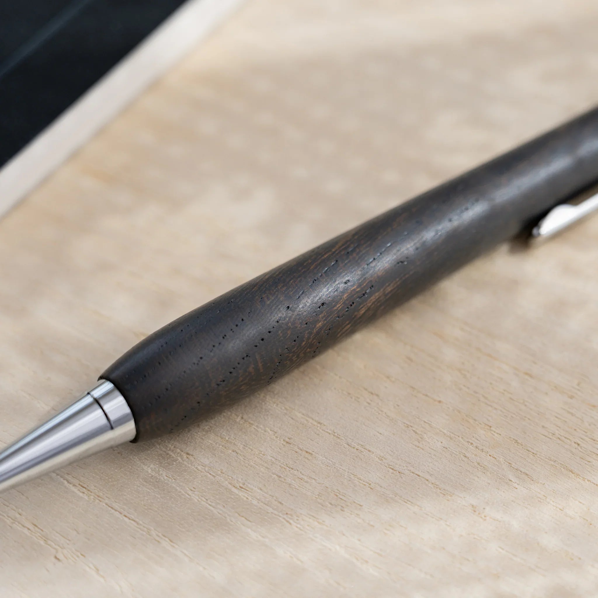 Charcoal black zelkova wood urushi mechanical pencil, close-up of barrel grain and silver clip, Japanese keyaki