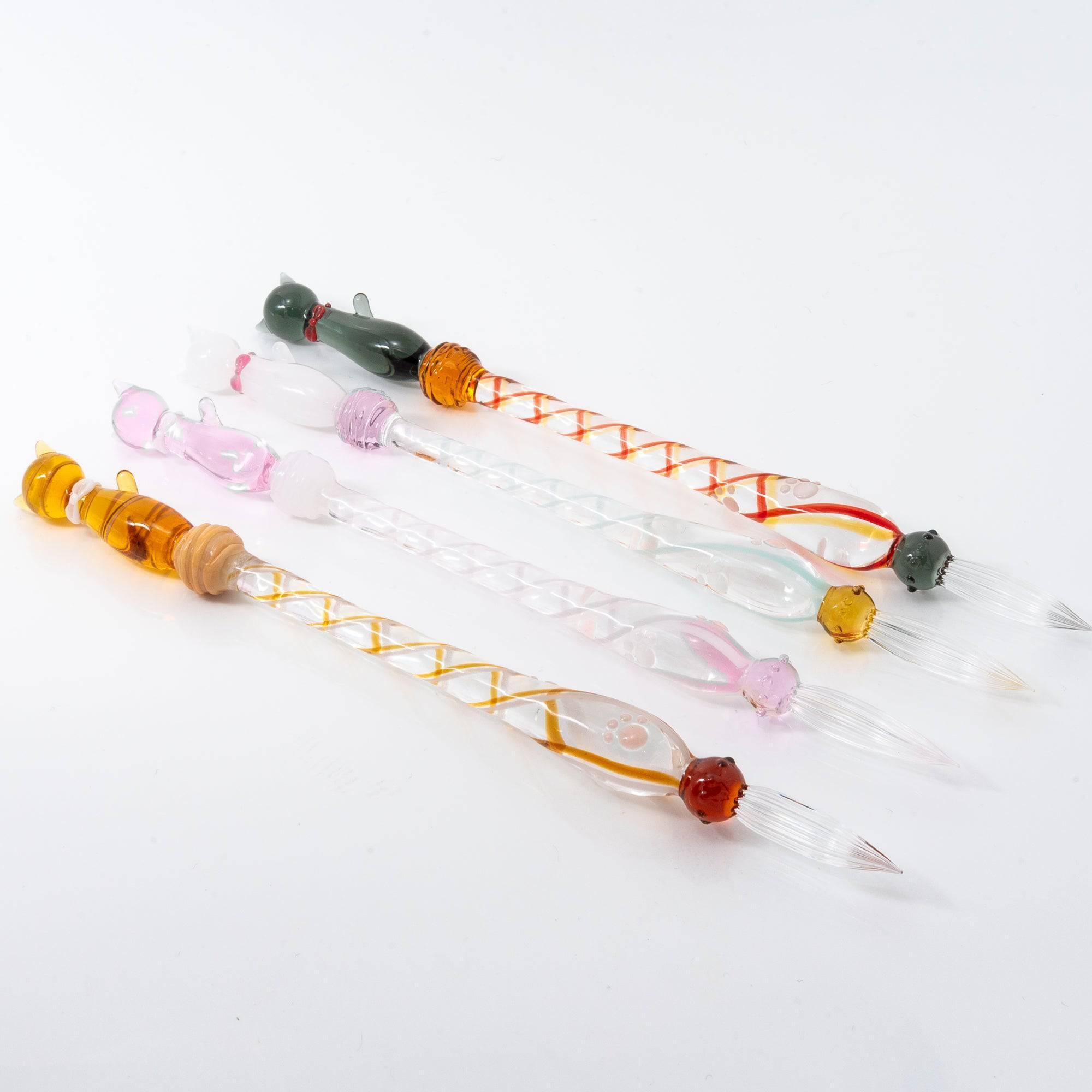 Five colorful glass dip pens with cat designs and twisted handles, each showcasing unique vibrant accents in pink, orange, and green.