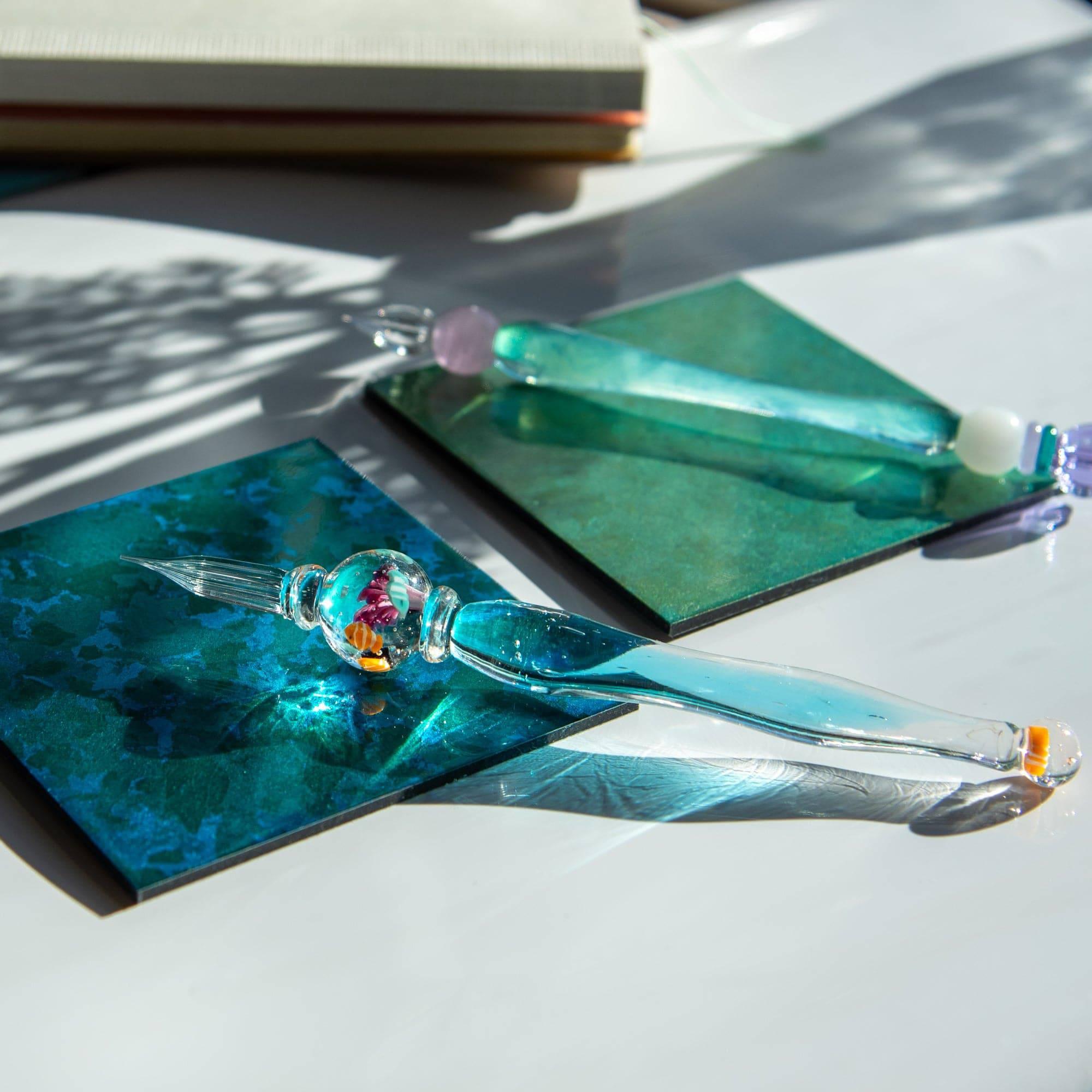 Two glass pens with clownfish and other fish motifs, resembling aquariums, on tiles. Great for Japanese stationery fans.